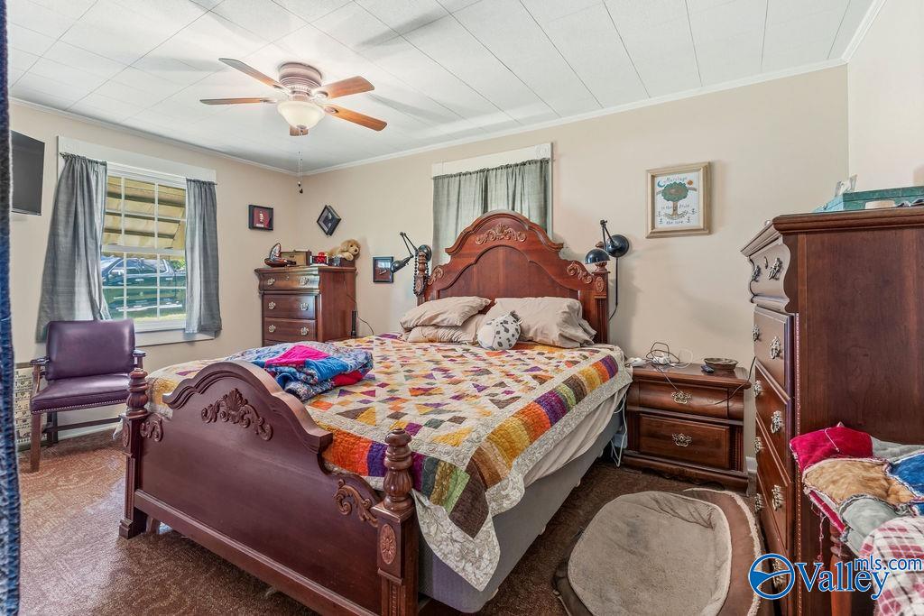 Bedroom with a carved wooden bed, colorful patchwork quilt, and matching wooden dressers.