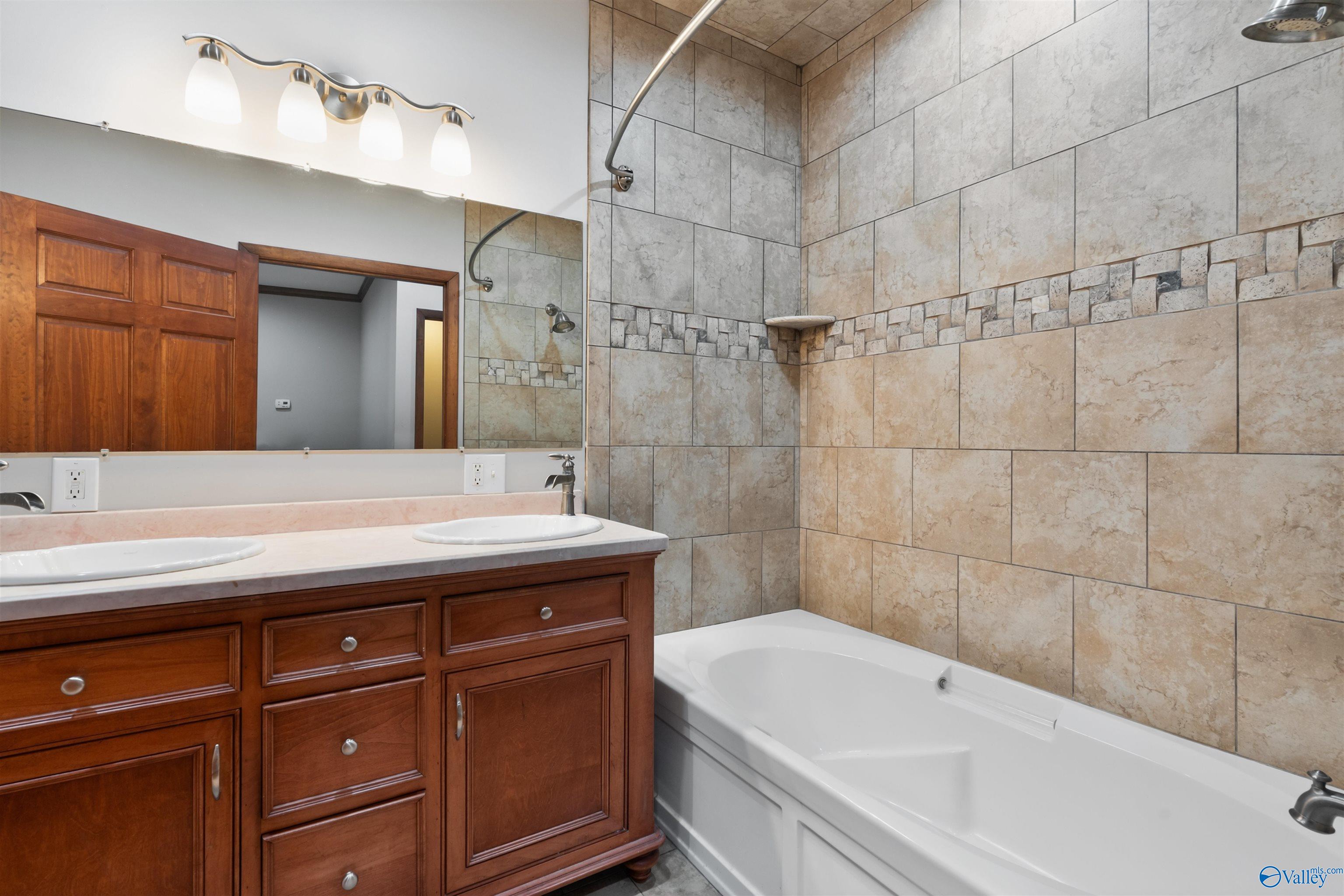 Bathroom with a tiled tub-shower and dark wood double-sink vanity.