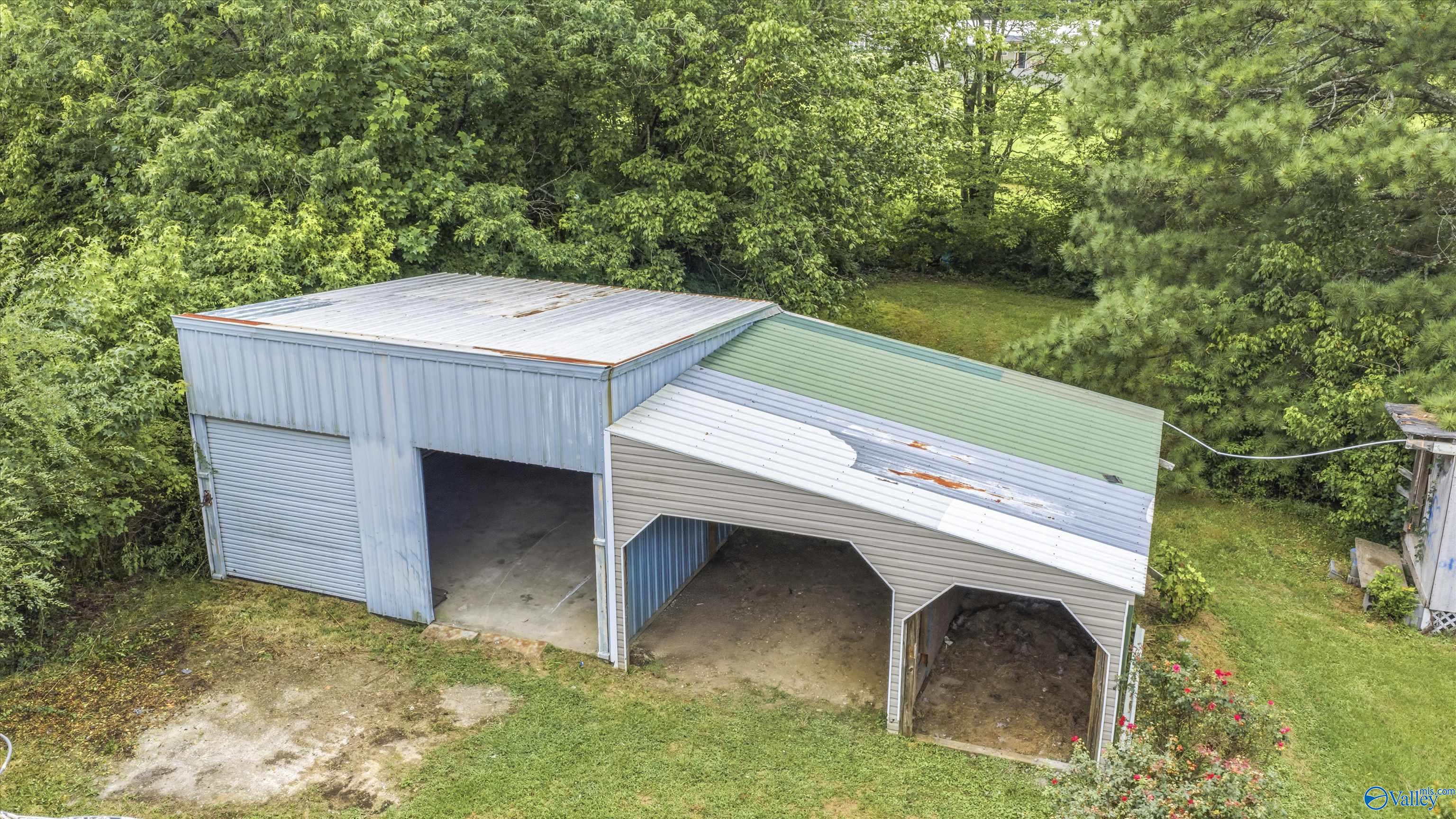 Aerial view of a metal outbuilding with a garage door and two open-sided bays.