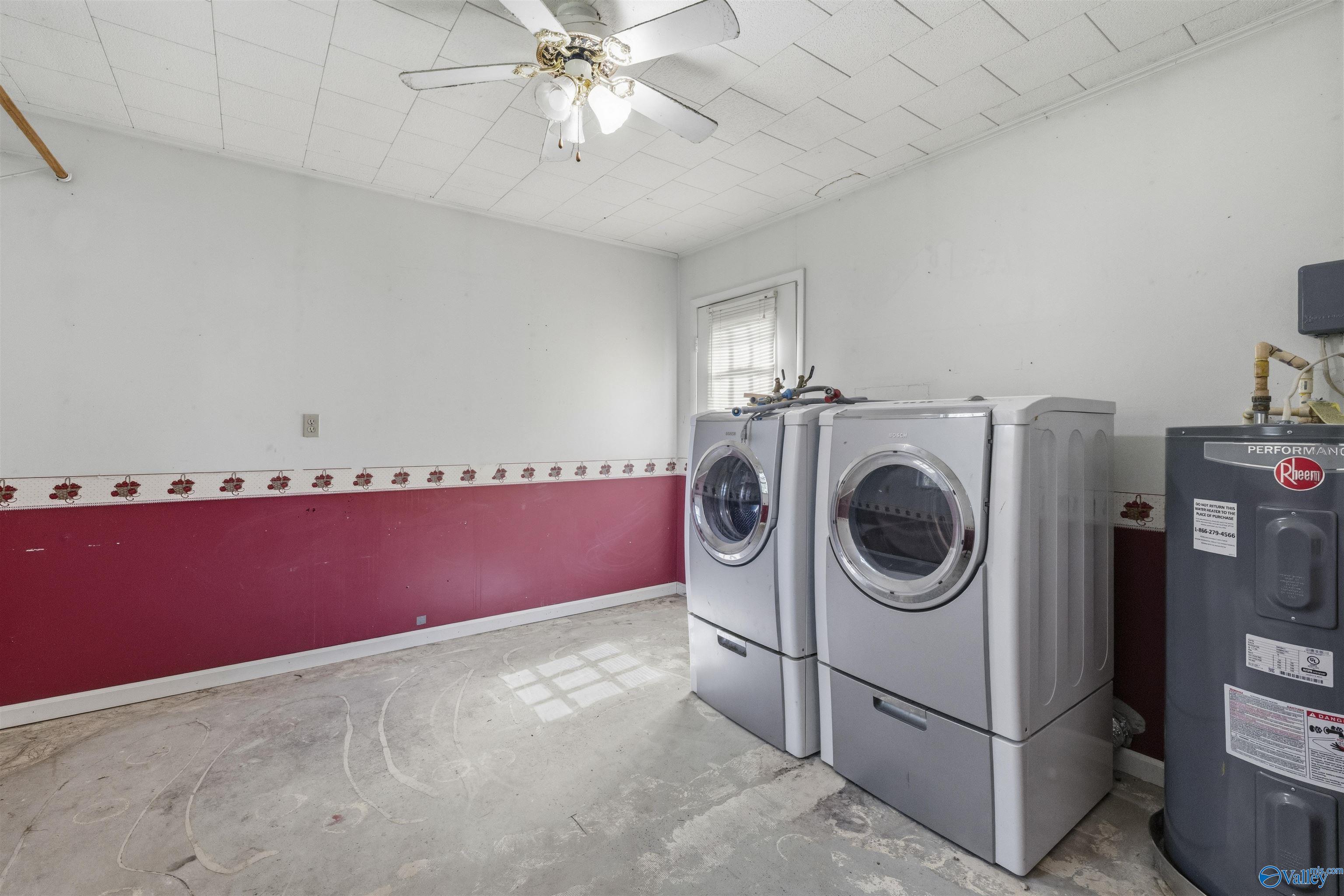 Laundry room with front-loading washer and dryer beside a Rheem water heater.