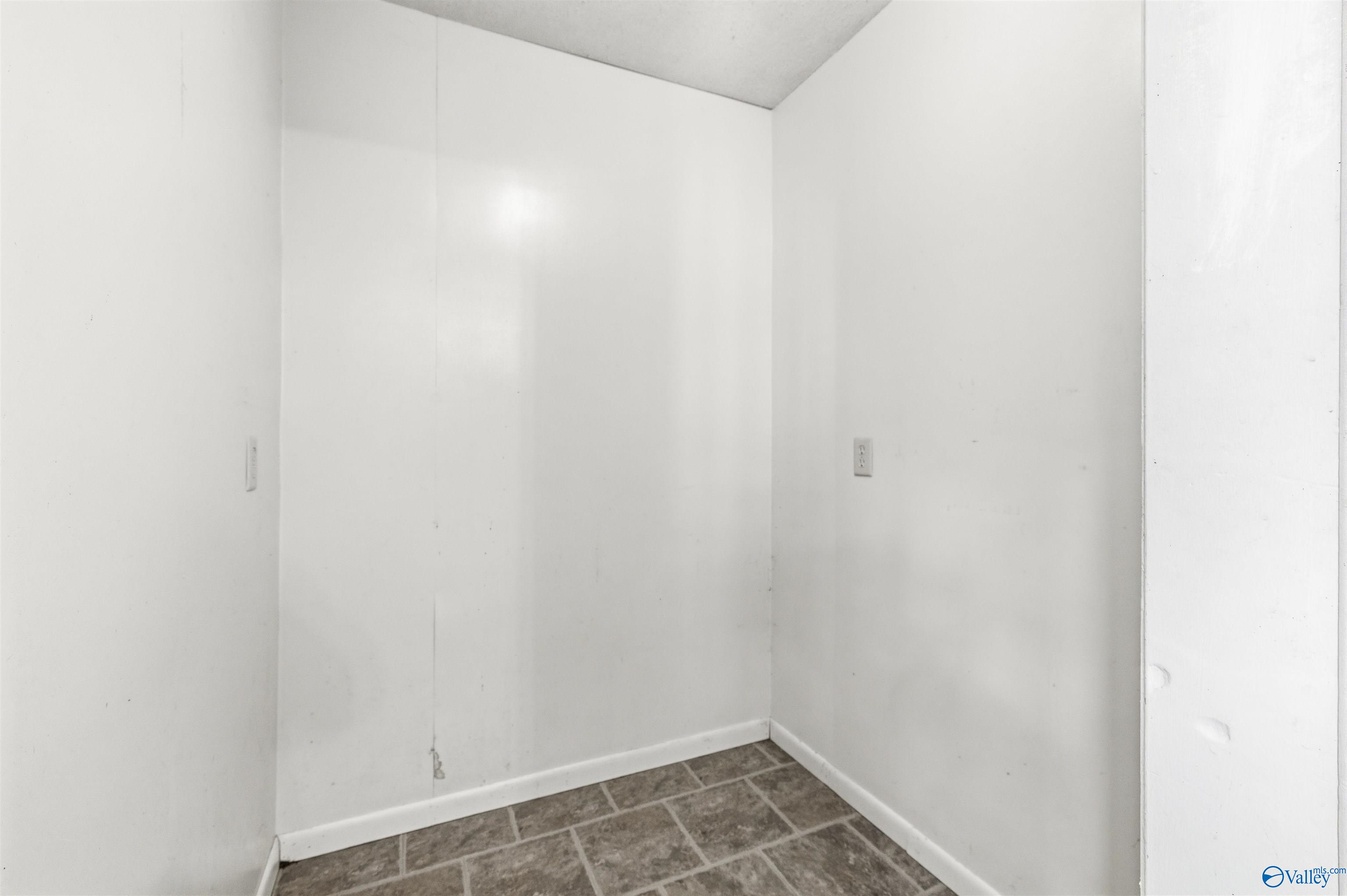 Empty room with white walls and gray-brown tiled flooring.