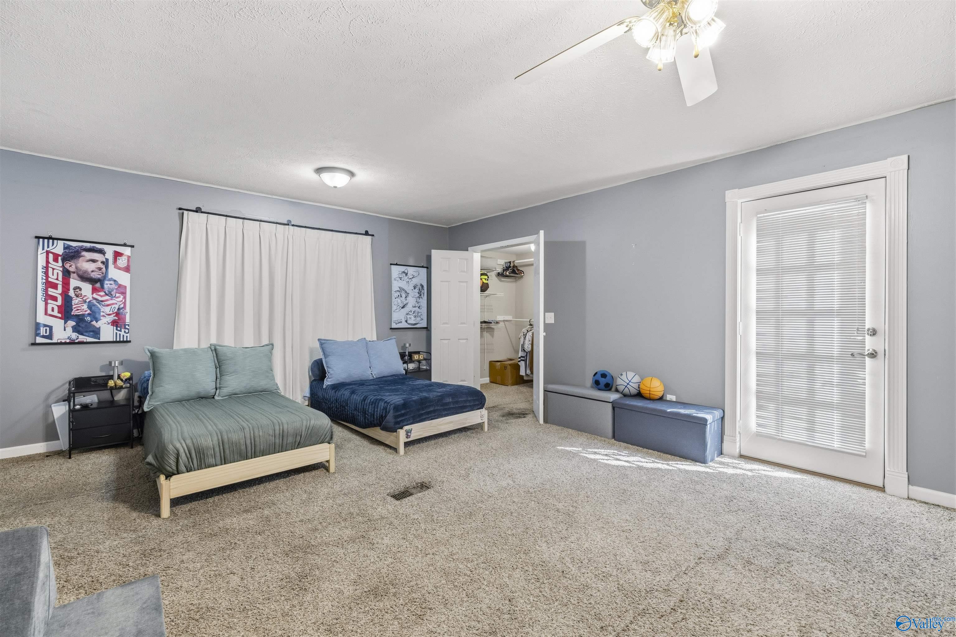 Bedroom with two low beds, soccer poster, open closet, and glass-paneled exterior door.
