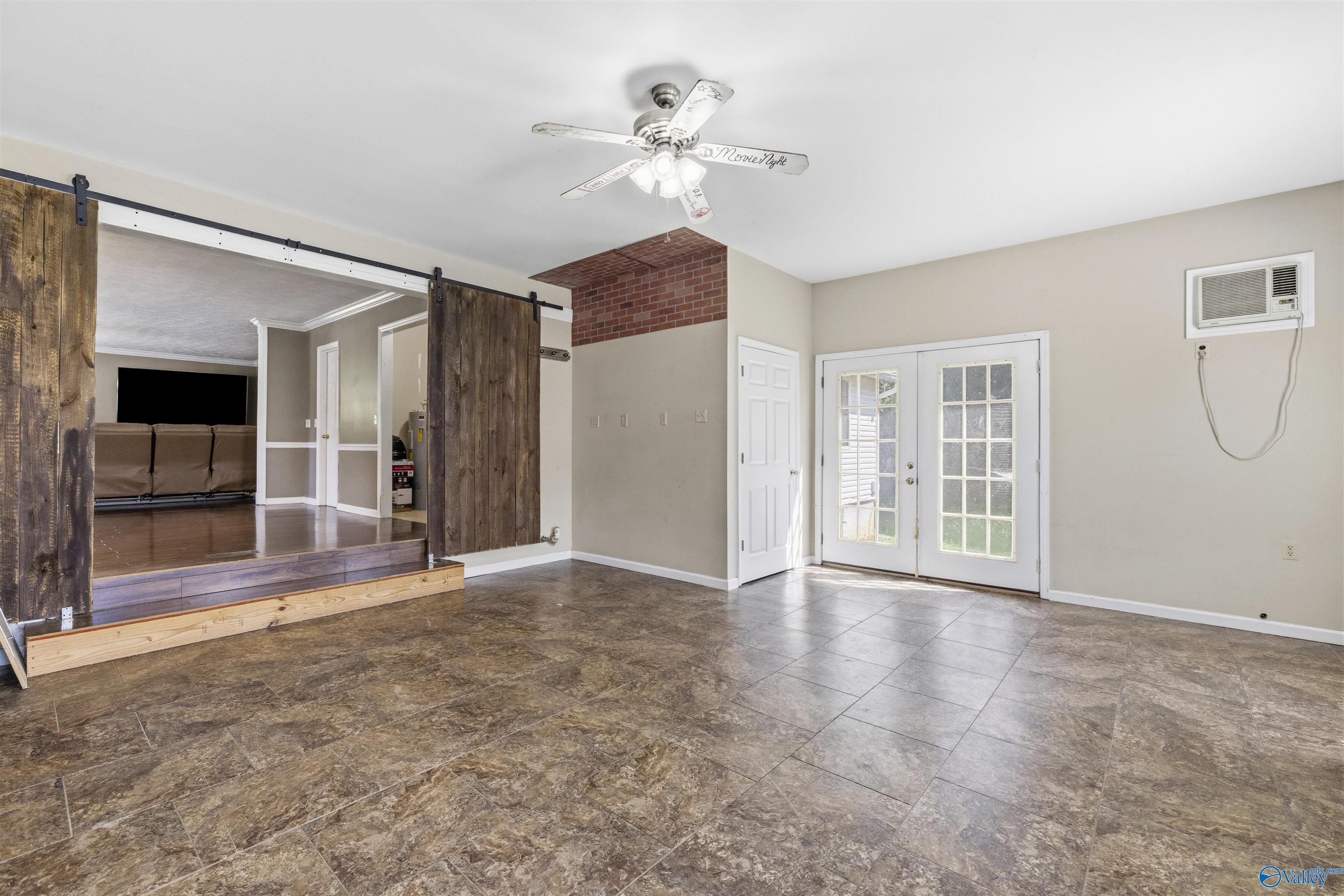 Tile-floored room with French doors and rustic sliding barn doors opening to a raised sitting area.