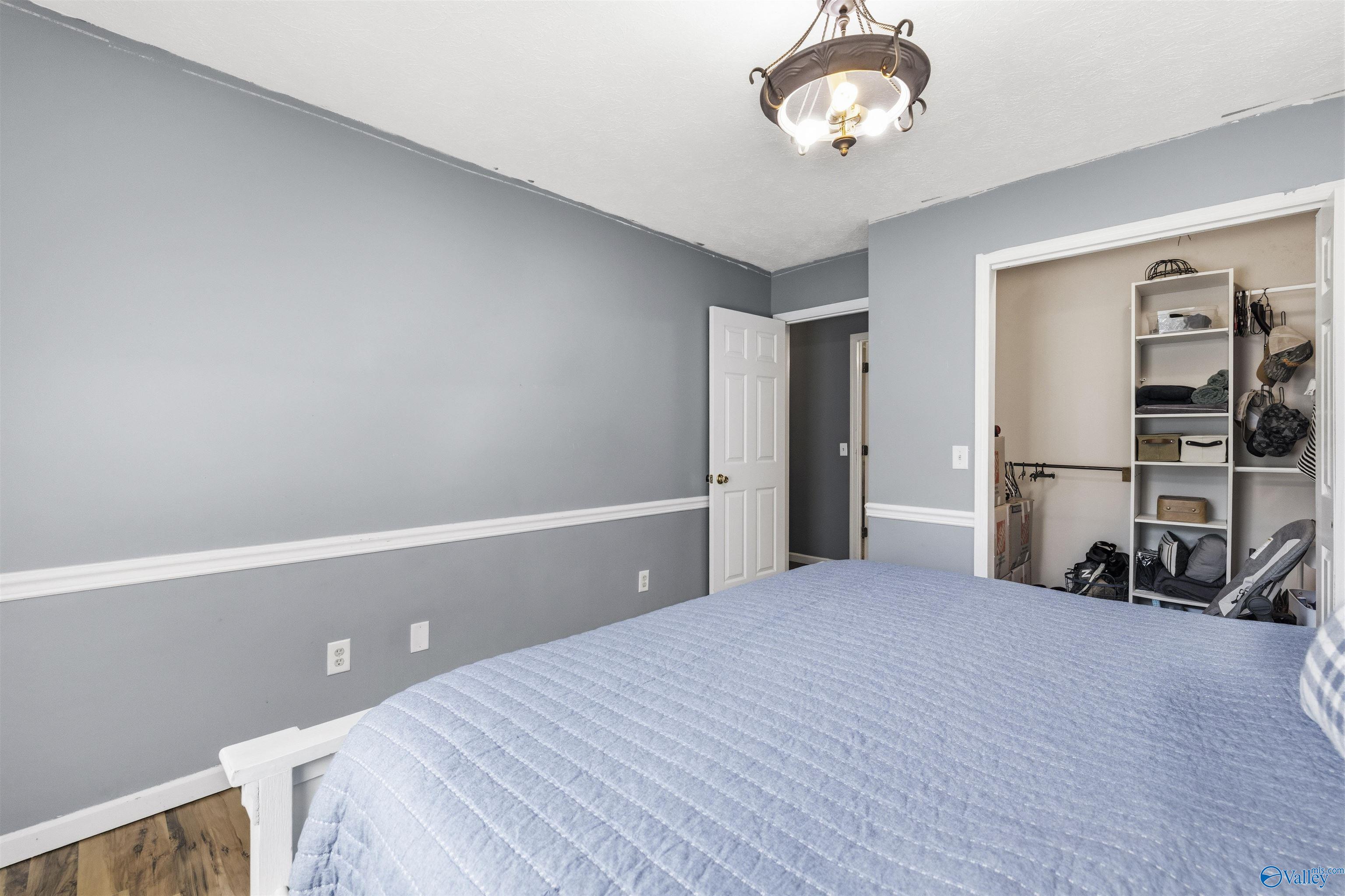 Bedroom with a light blue quilted bed and an open, organized closet.