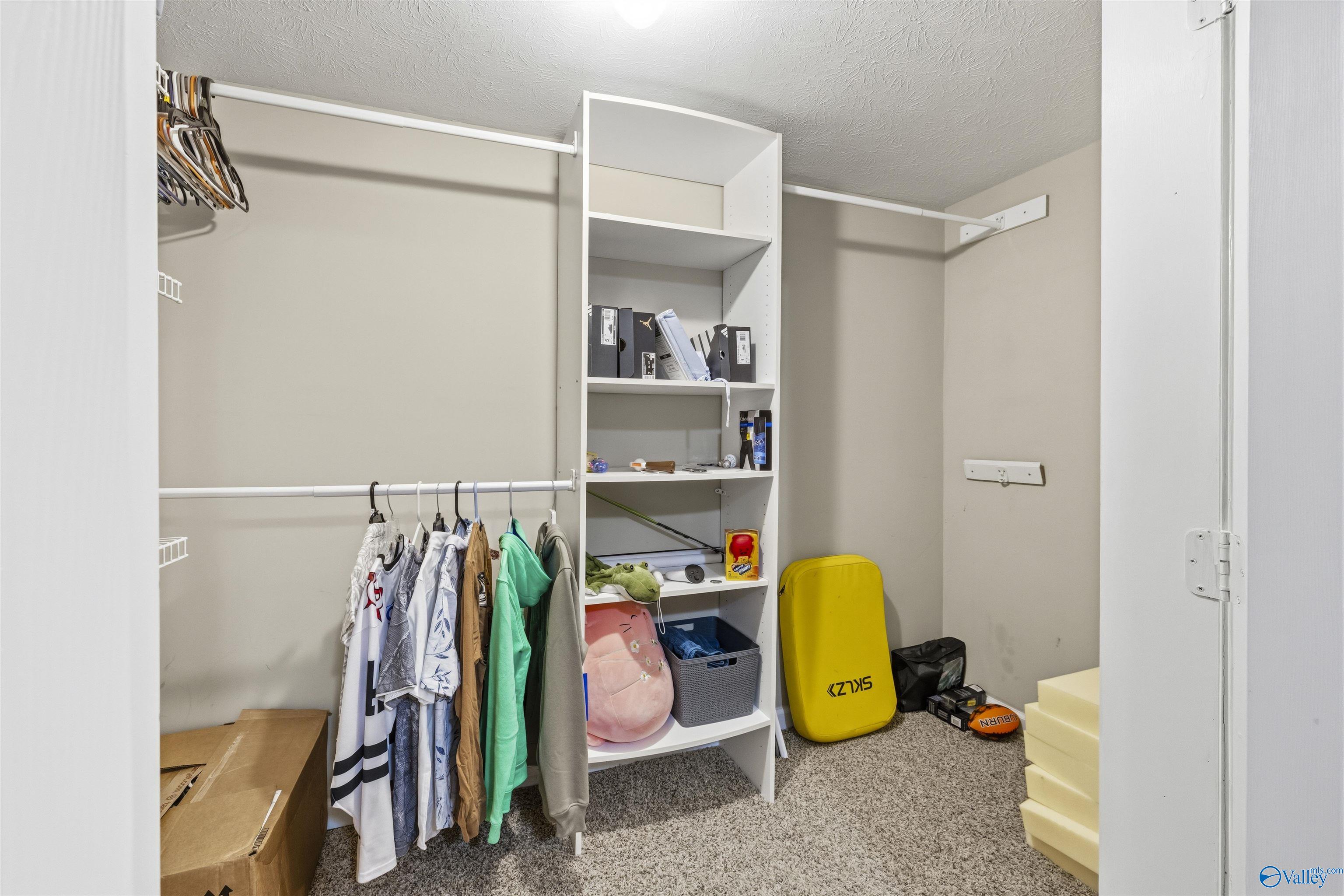 Walk-in closet with built-in shelves, hanging clothes, and sports equipment.