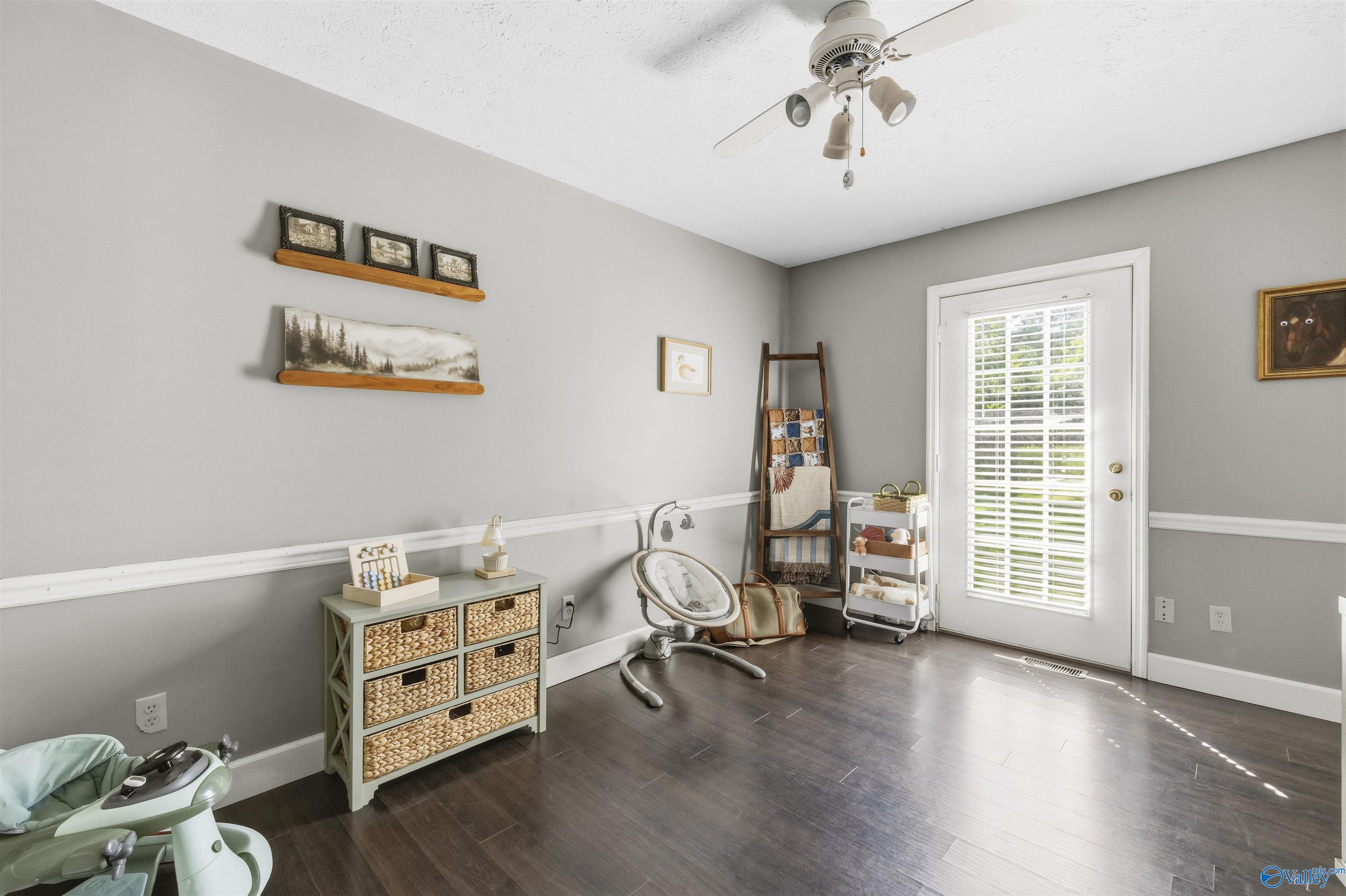 Furnished nursery with a baby swing, woven-basket dresser, and door with a tall window.