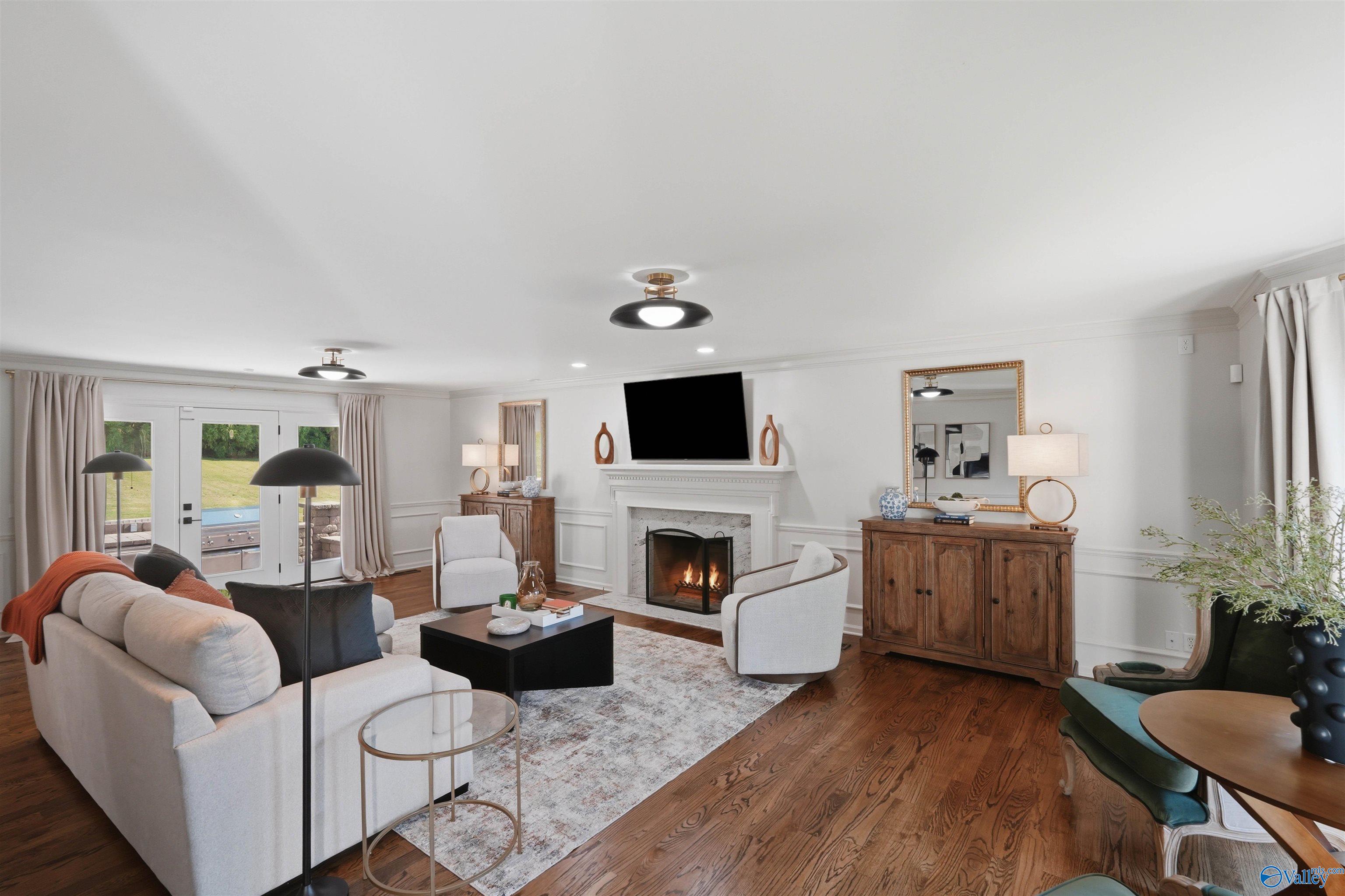 Staged living room with a fireplace, hardwood floors, and French doors to the yard.