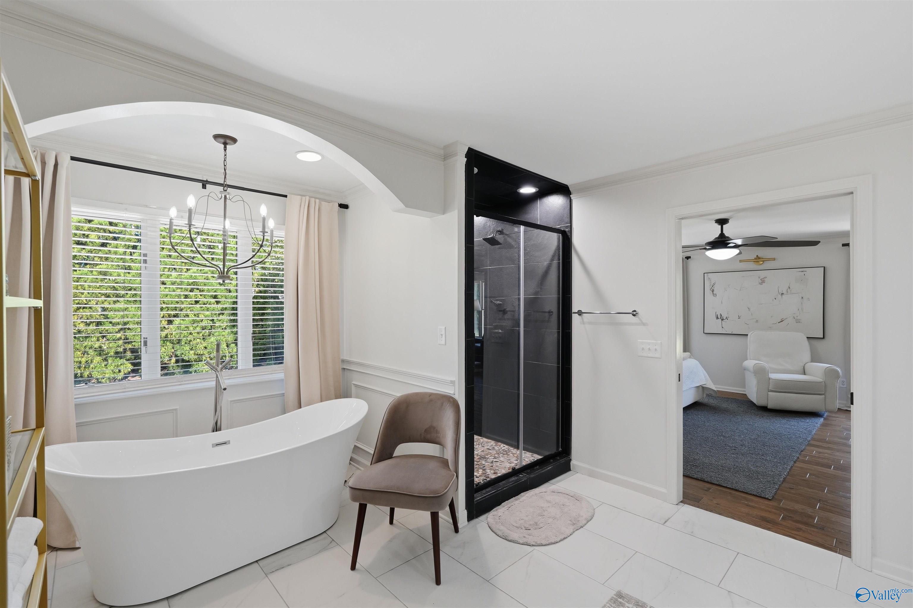Bathroom with a freestanding tub, large window, and black-tiled glass shower.