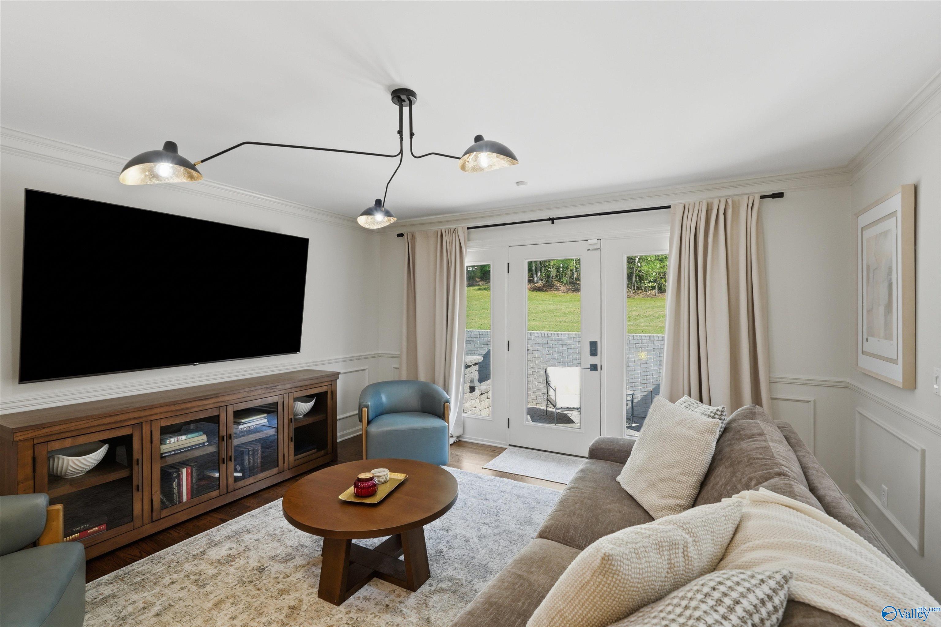 Furnished living room with wall-mounted television, gray sofa, and glass doors opening to a patio.