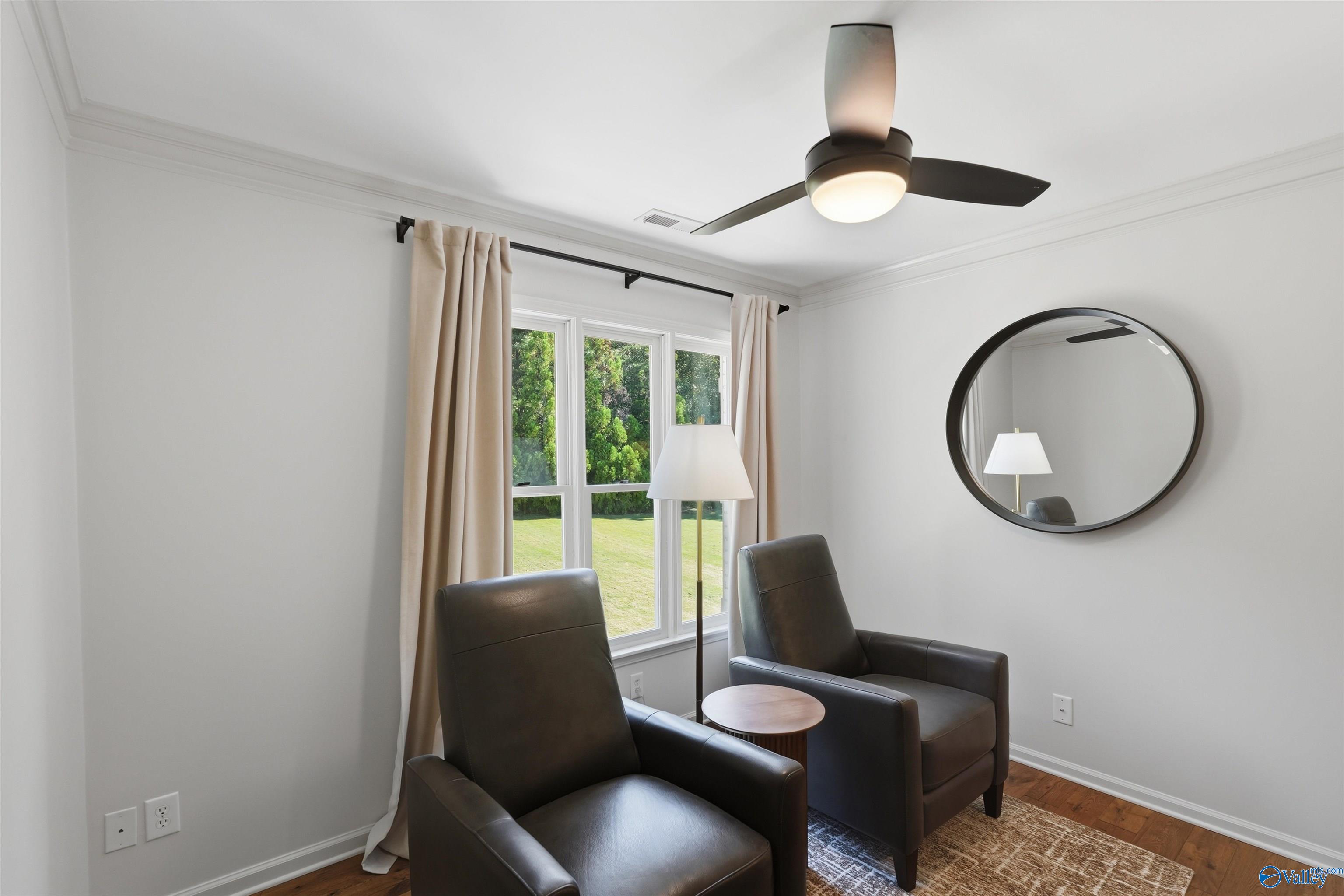 Sitting area with two dark leather armchairs beside windows overlooking a green lawn.
