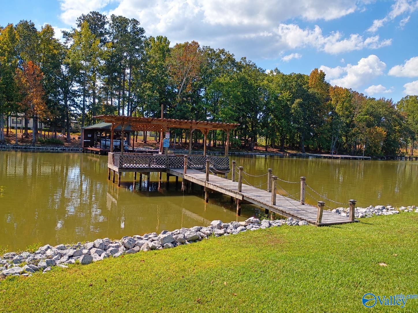 Covered wooden dock and walkway extending over a lake, with a tree-lined shore.