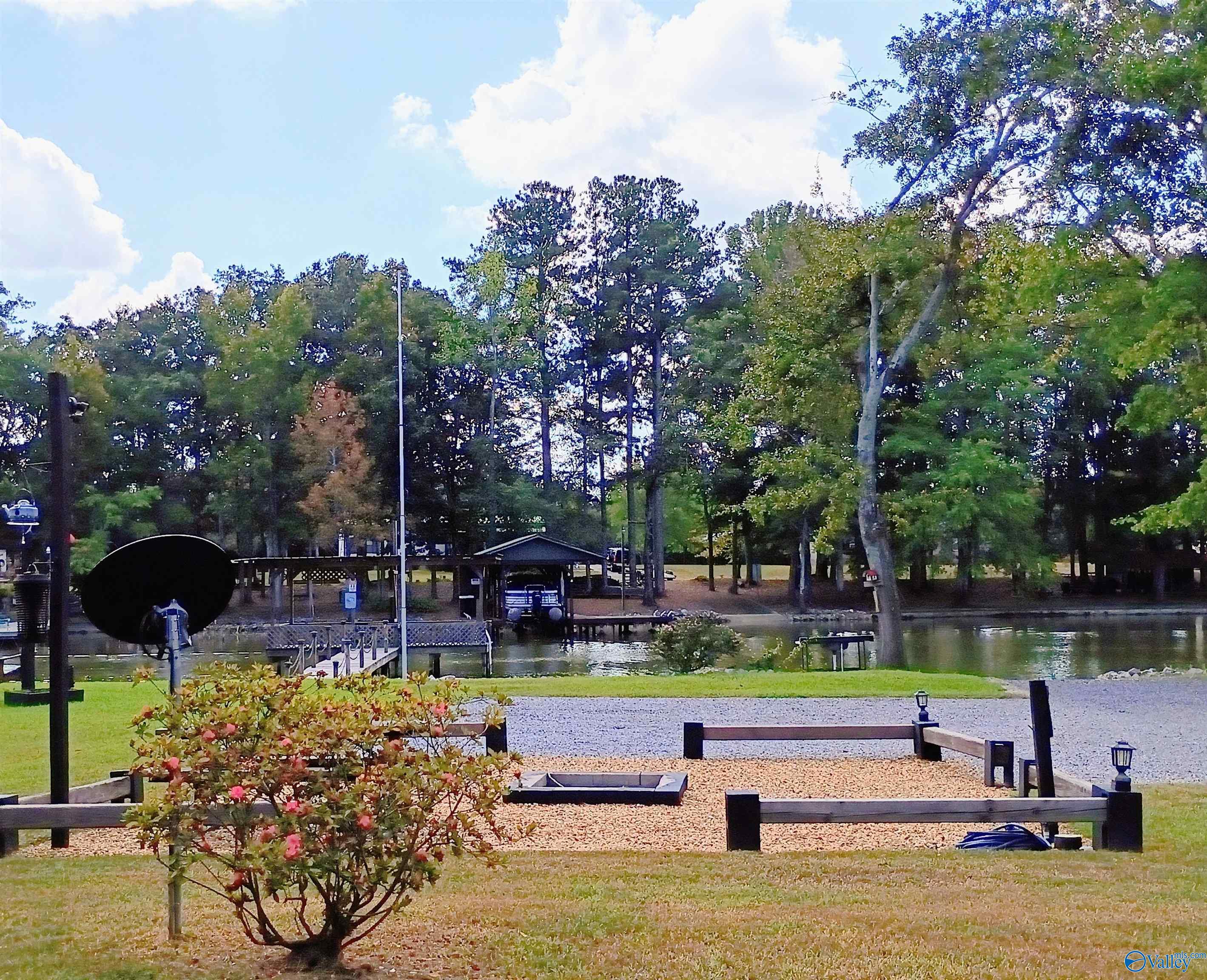 Waterfront yard with a gravel patio and fire pit overlooking a dock and covered boat shelter.