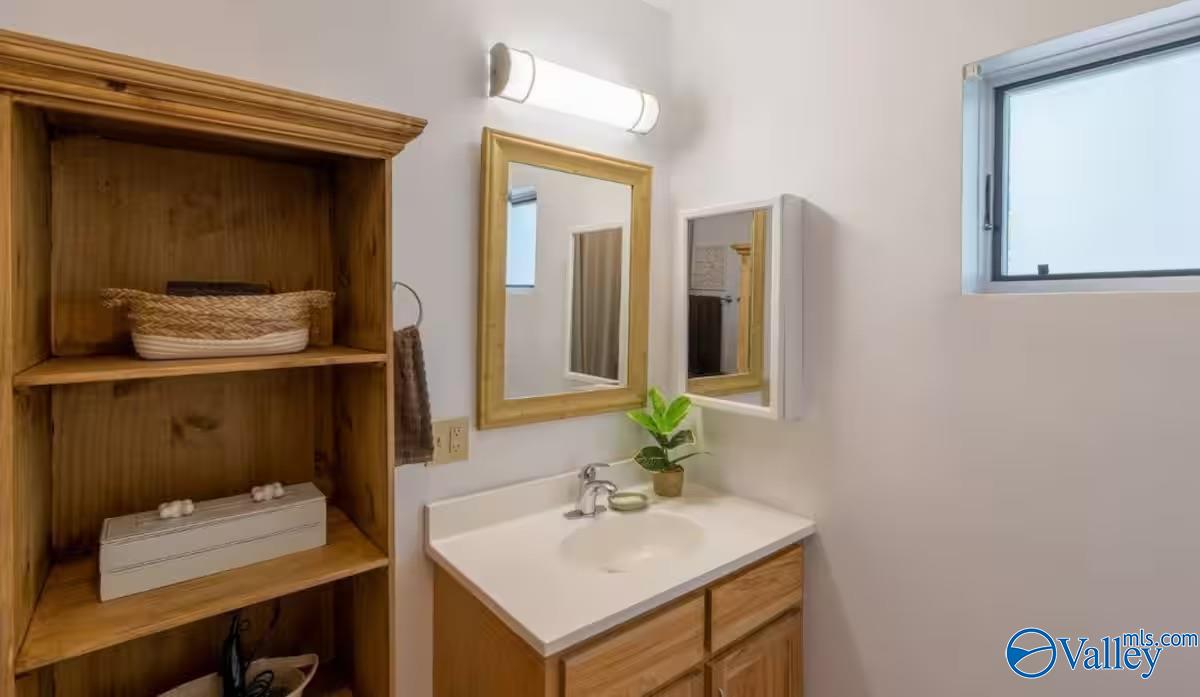 Bathroom vanity with wood drawers, wall mirrors, and built-in wooden shelving.