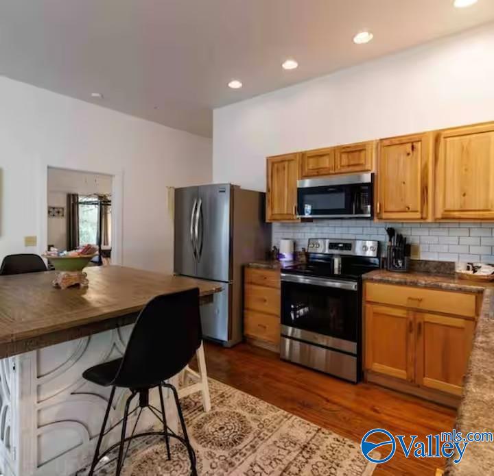 Kitchen with honey-colored cabinets, stainless steel appliances, and a wood-topped island.