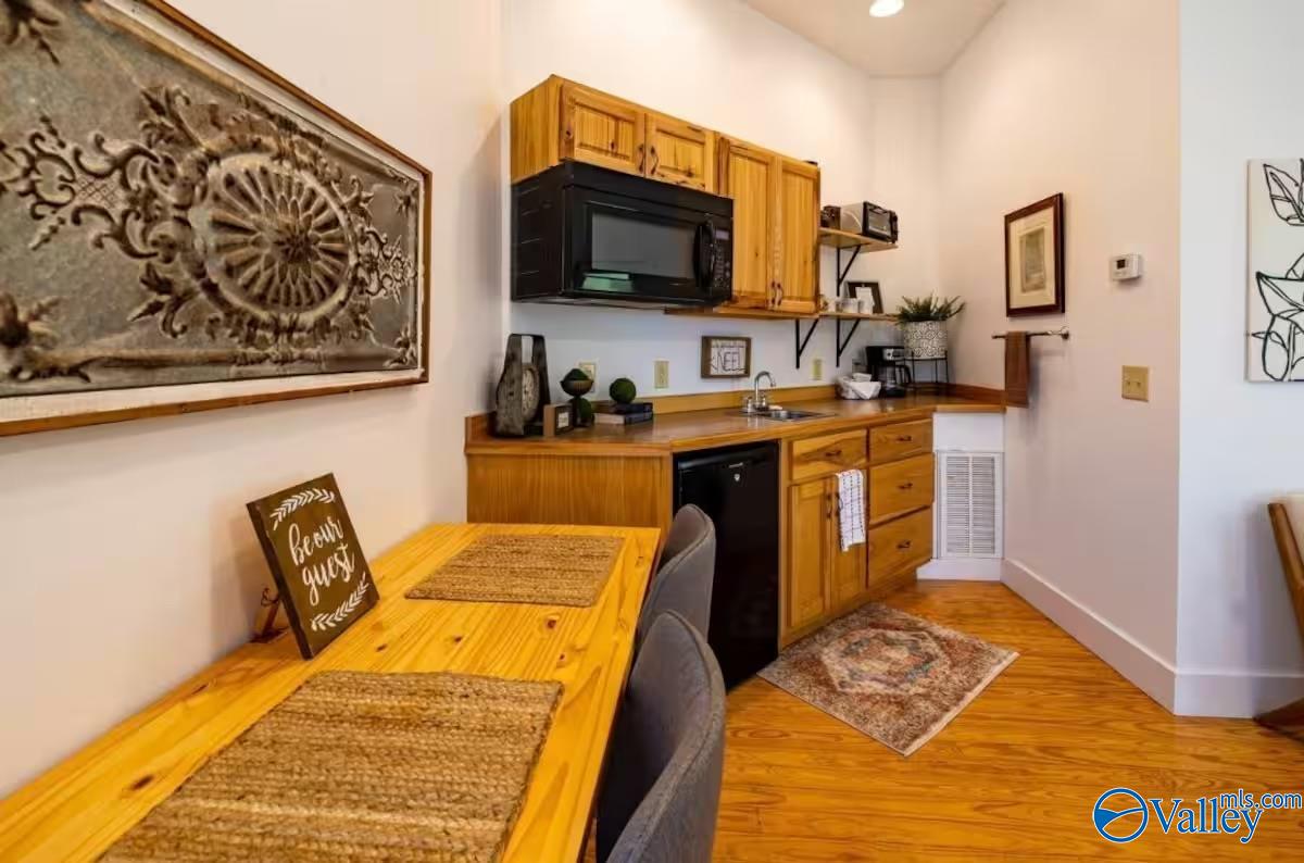 Kitchenette with honey-colored cabinets, microwave, and a wooden dining table.
