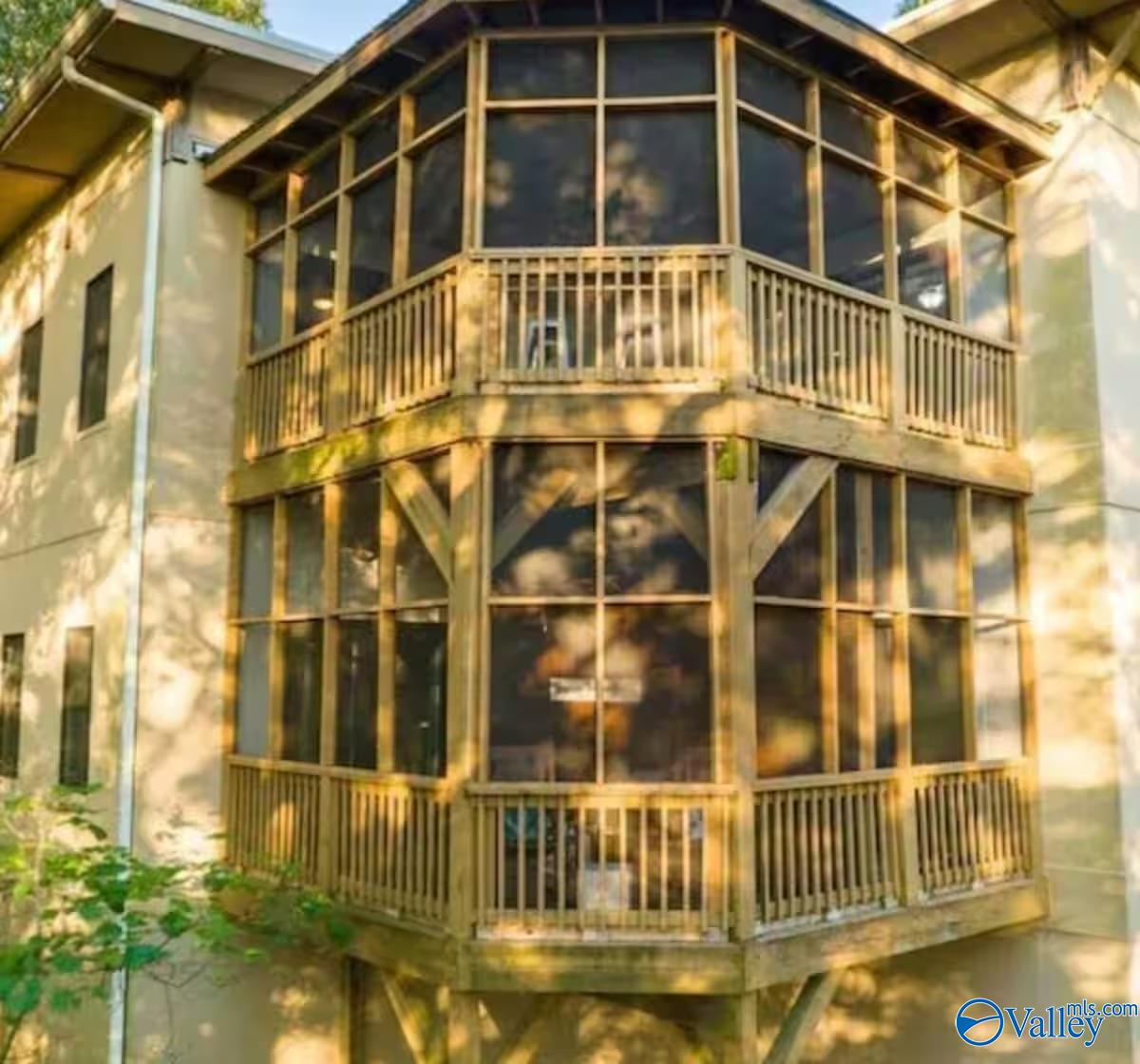 Home with a two-story enclosed sunroom and wooden balcony railings.