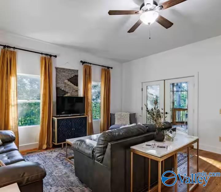 Furnished living room with leather seating, golden curtains, and French doors.