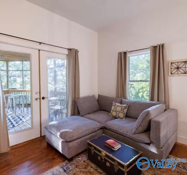 Living room with a gray sectional and trunk coffee table beside glass doors opening to a deck.