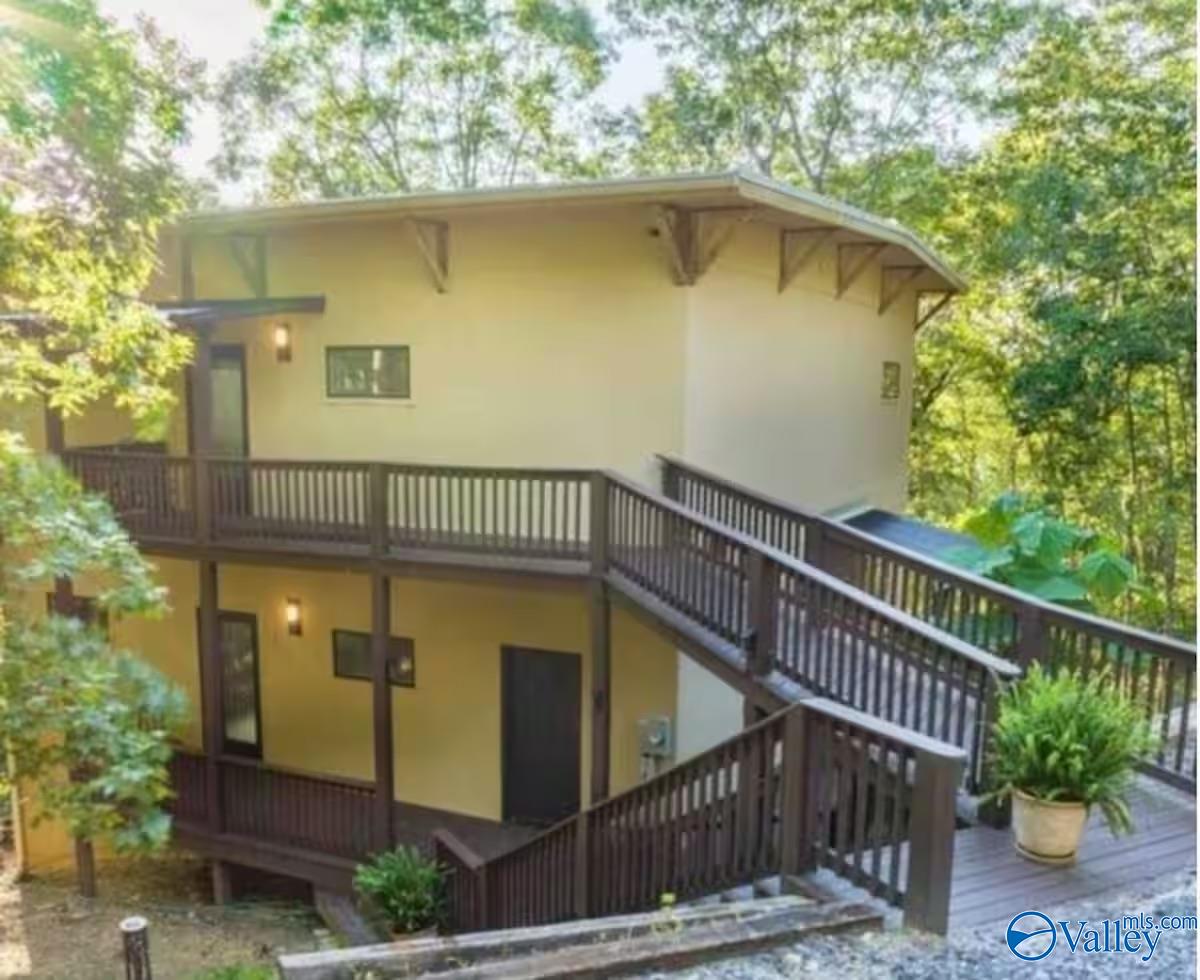 Two-story home surrounded by trees, with dark wooden decks and elevated walkways.