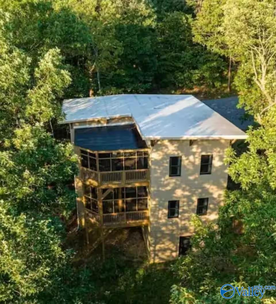 Elevated view of a two-story home with screened porches surrounded by dense trees.