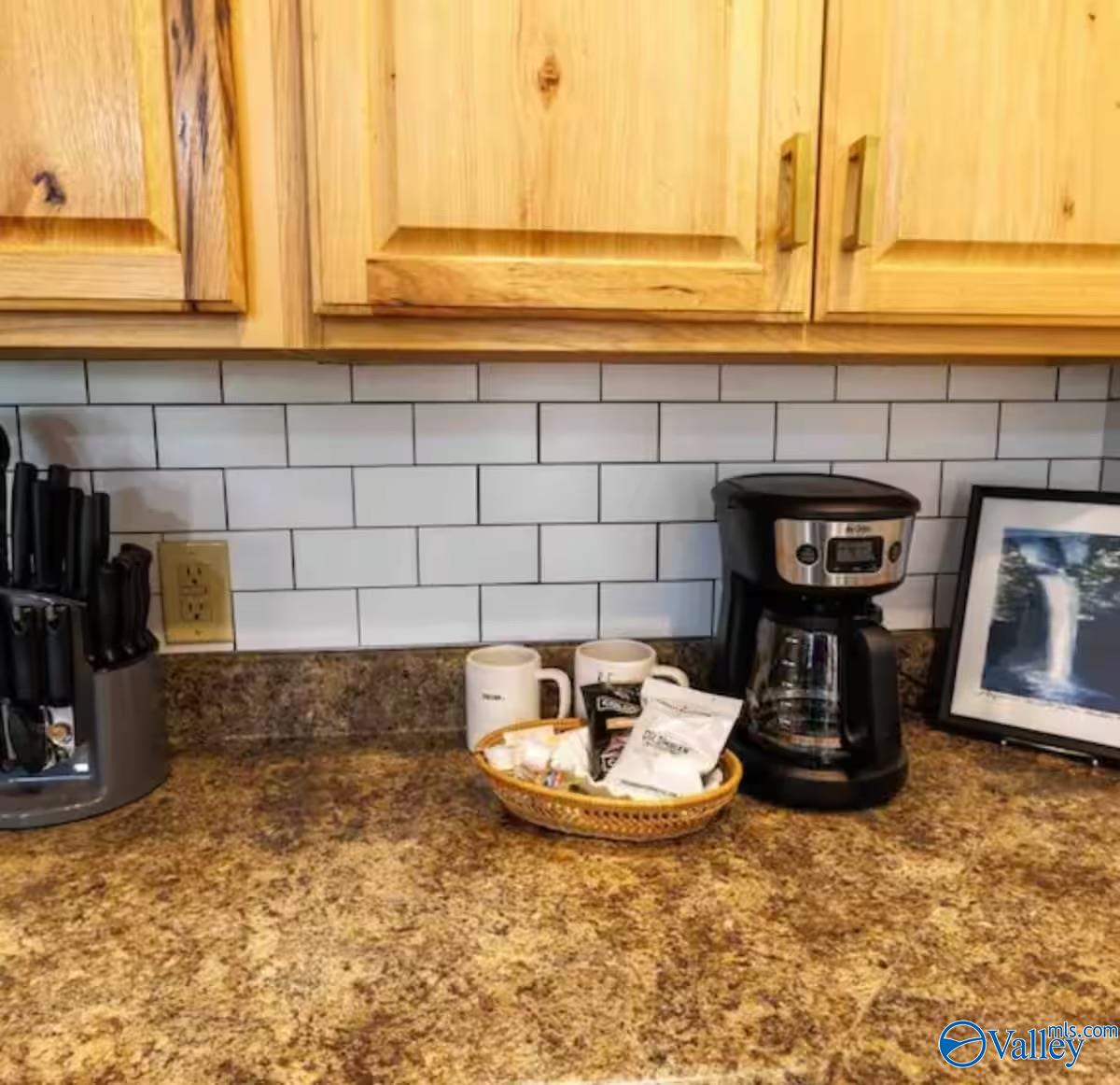 Kitchen counter with granite, wood cabinets, subway tile, and a coffee station.