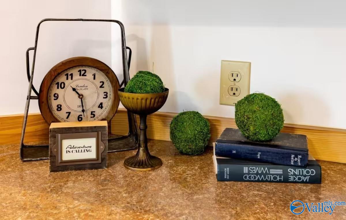 Staged countertop display with a vintage clock, greenery, books, and an “Adventure Is Calling” sign.
