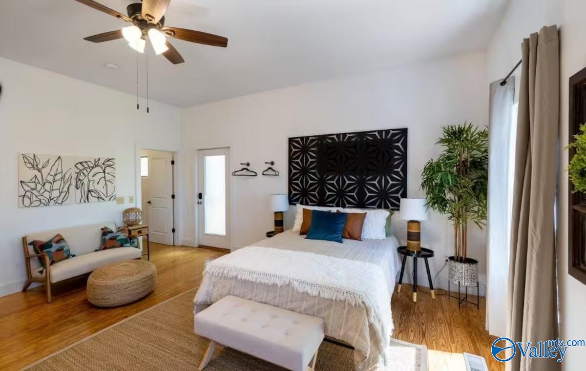 Staged bedroom with a white bed, geometric black headboard, and a small sitting area.