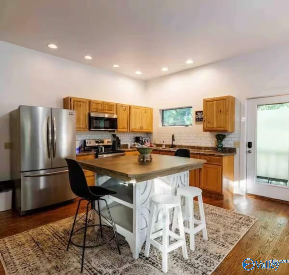 Kitchen with wood cabinets, stainless steel appliances, and a large island with seating.