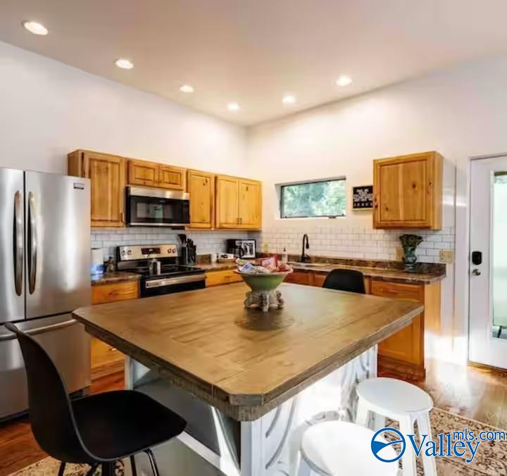 Kitchen with wooden cabinets, stainless steel appliances, and a large island with seating.