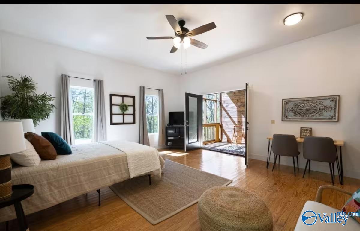 Bedroom with a bed and hardwood floors, opening onto a covered porch.