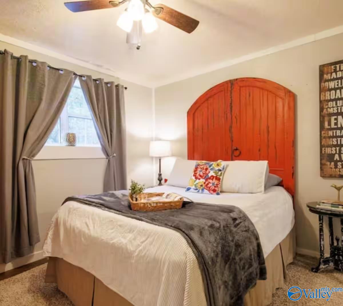 Bedroom with an arched red wood headboard, white bedding, and gray curtains.