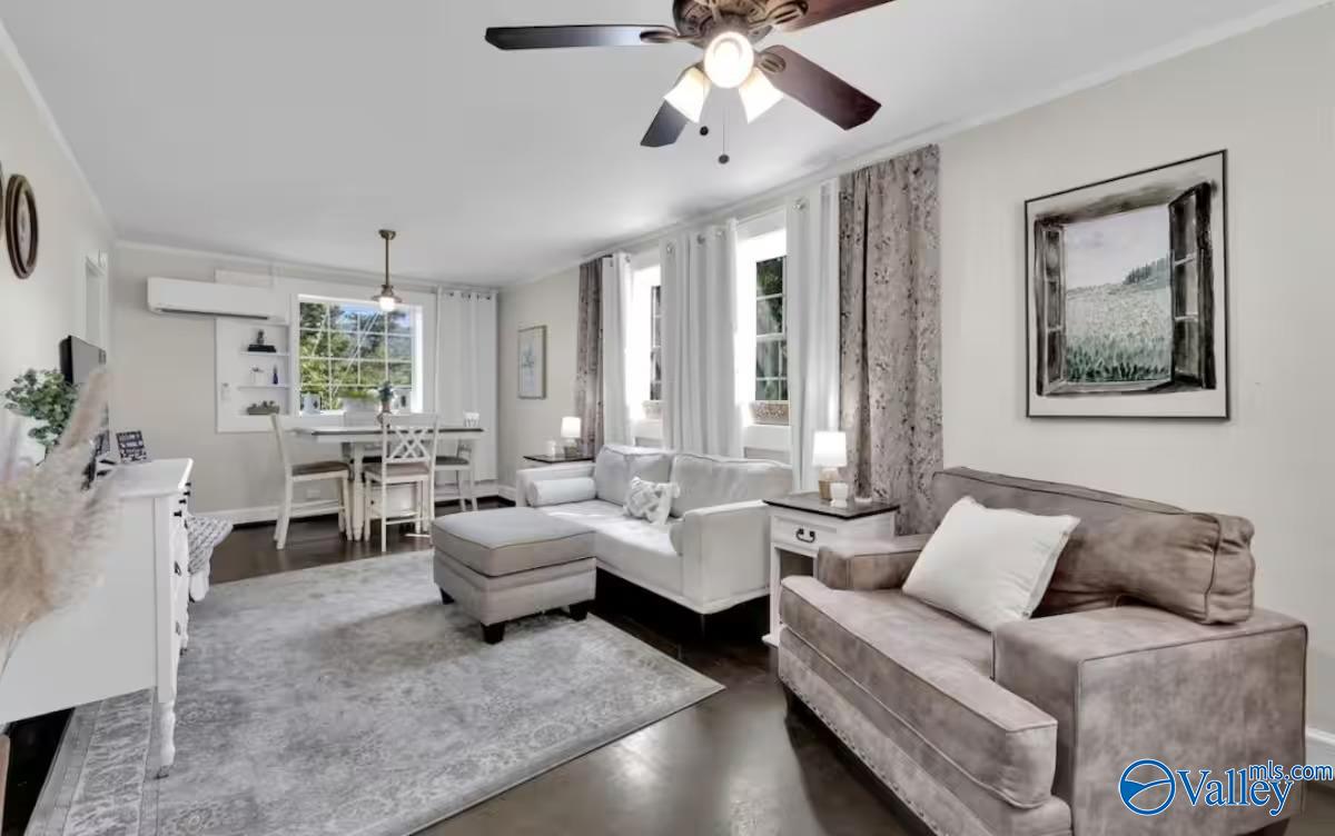 Staged living room with white and taupe sofas, gray rug, and adjoining dining area.