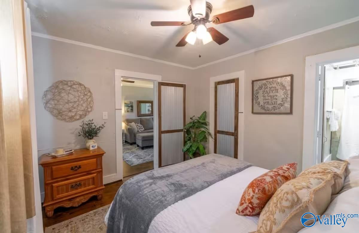 Bedroom with gray-and-white bedding, a wooden chest of drawers, and a ceiling fan.