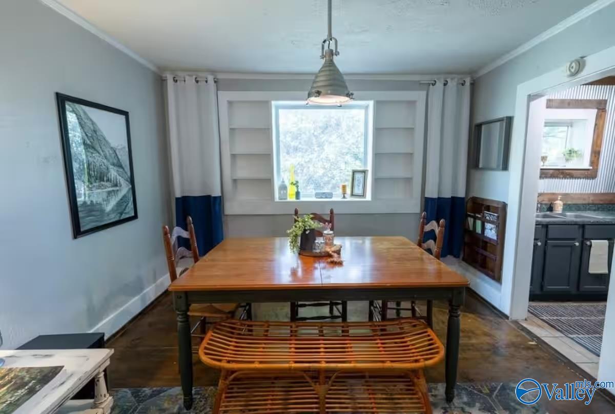 Dining room with a wooden table, bench seating, built-in shelves, and blue-and-white curtains.