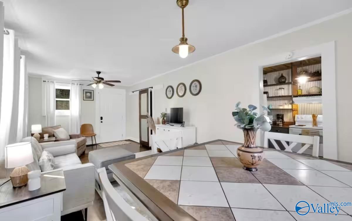 Furnished dining and living area with a geometric-tile table, white seating, and open kitchen.