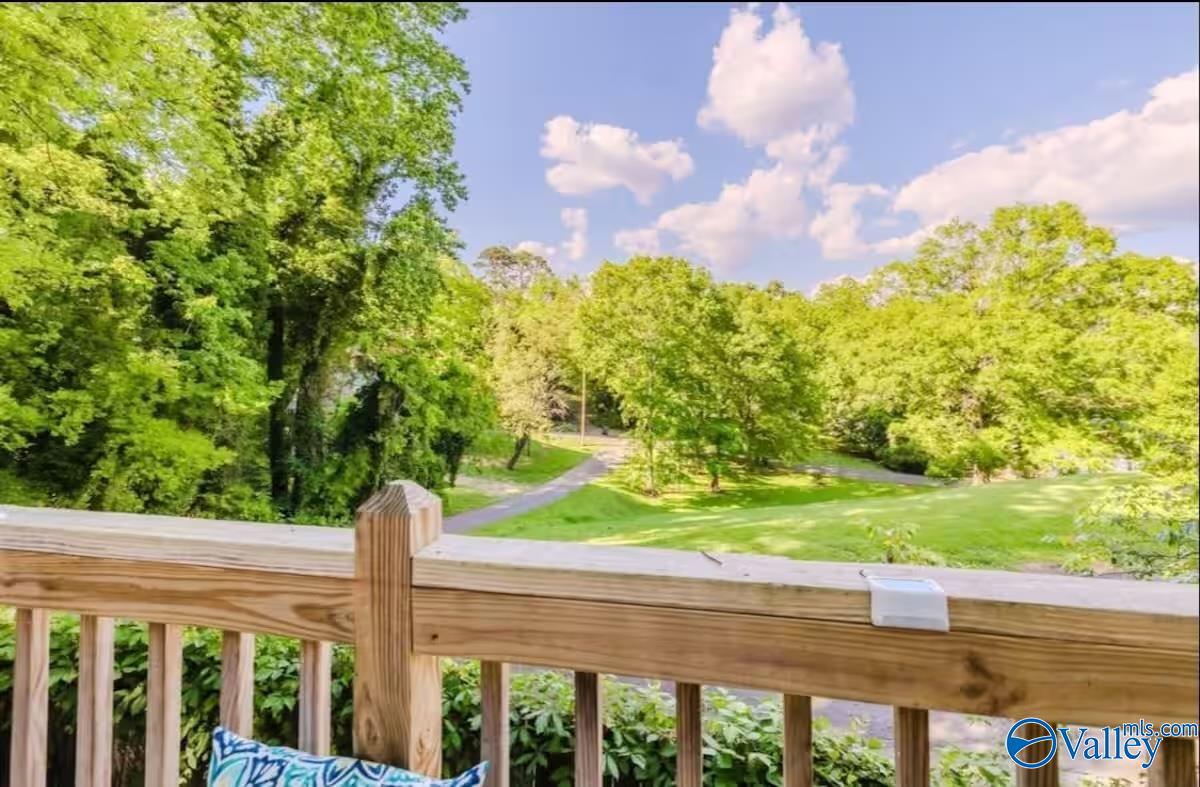 Deck overlooks a leafy yard with a winding path and mature trees.