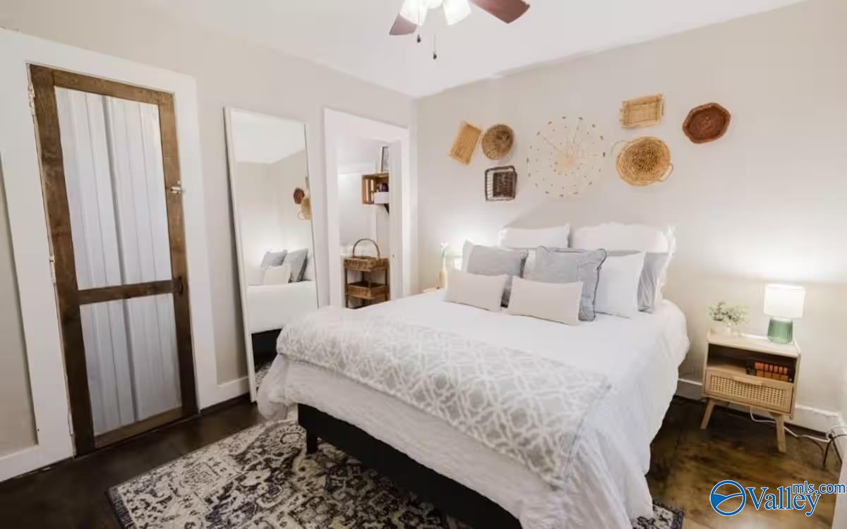 Bedroom with a white bed, woven wall decor, rustic sliding door, and patterned rug.