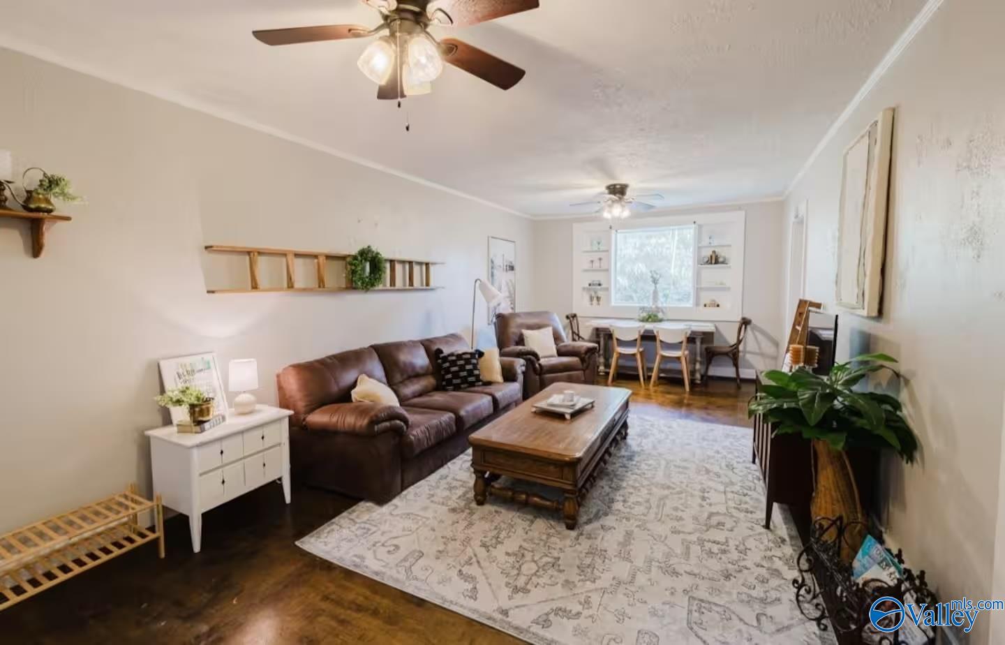 Living room with a brown leather sofa, patterned rug, and dining table beside the window.