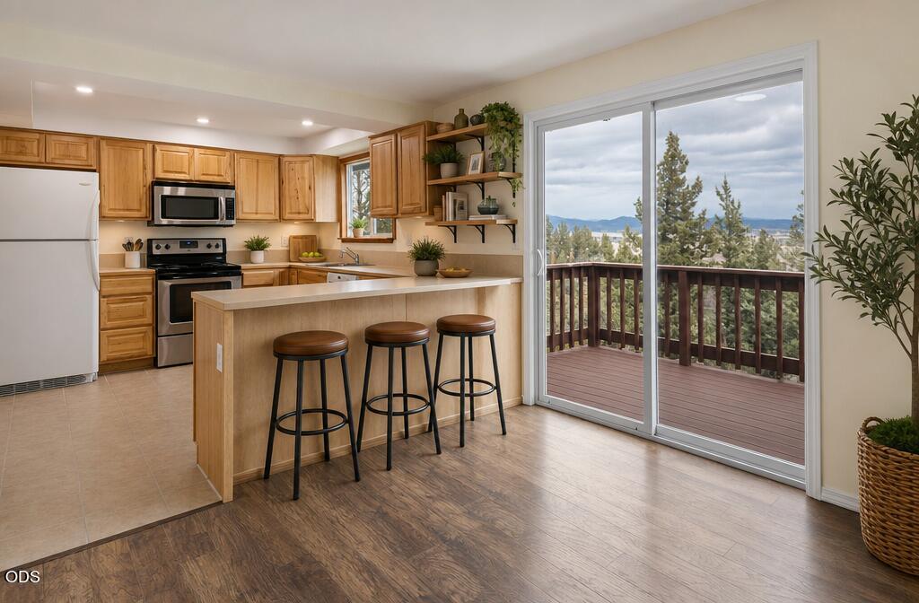 Kitchen with a wood-cabinet island, three stools, and sliding doors opening onto a deck with mountain views.