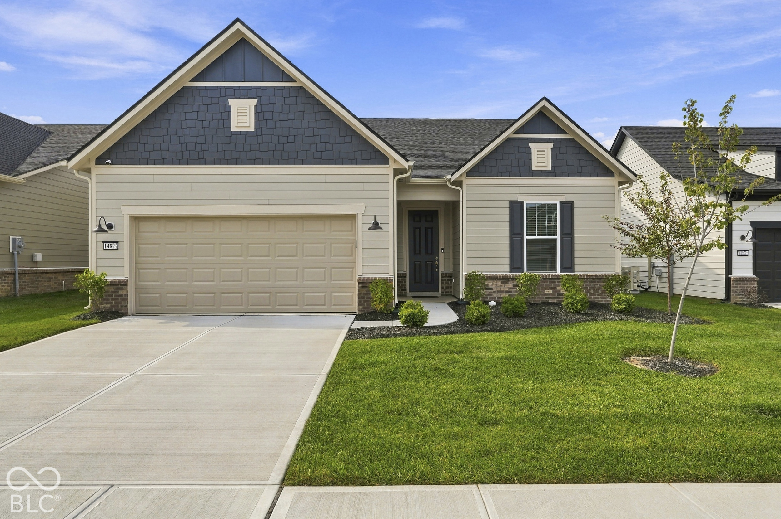 Gray-sided home with a two-car garage, landscaped lawn, and concrete driveway.