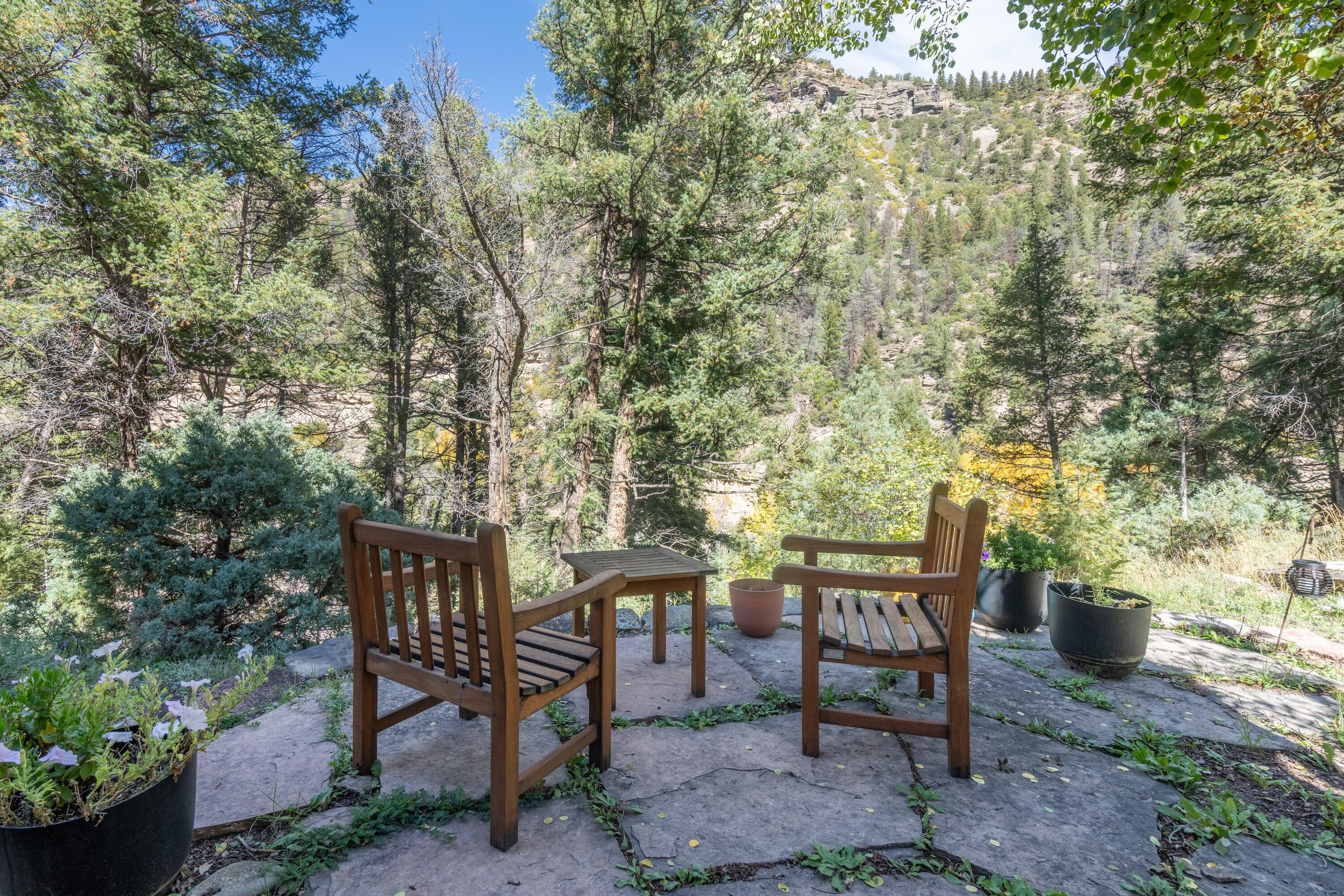 Stone patio with wooden chairs overlooking a wooded mountain slope.