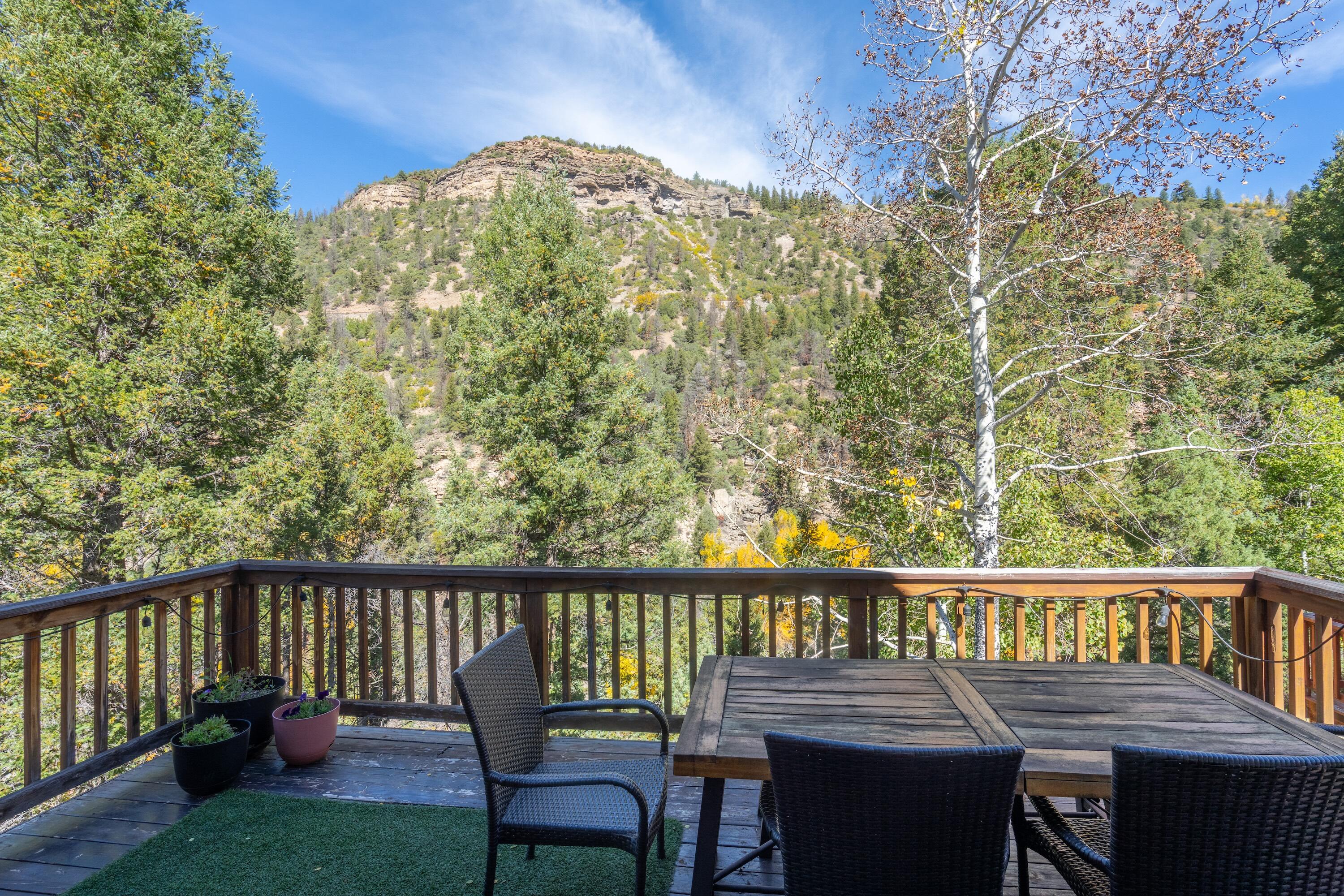 Deck with outdoor dining set overlooking a wooded mountain slope.