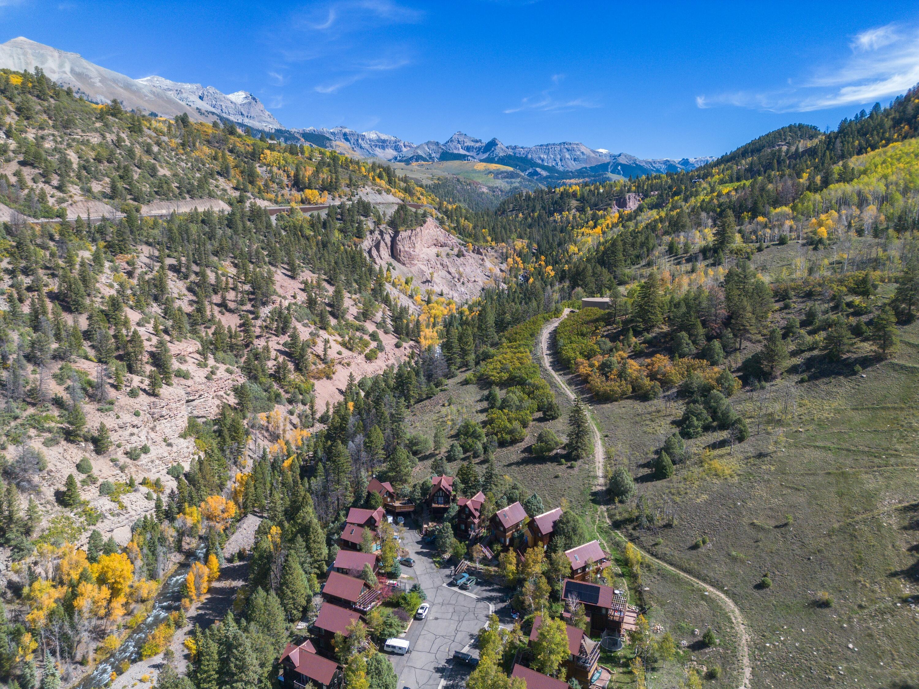 Aerial view of Two Rivers Drive homes beside a creek, surrounded by autumn-colored forest and mountains.