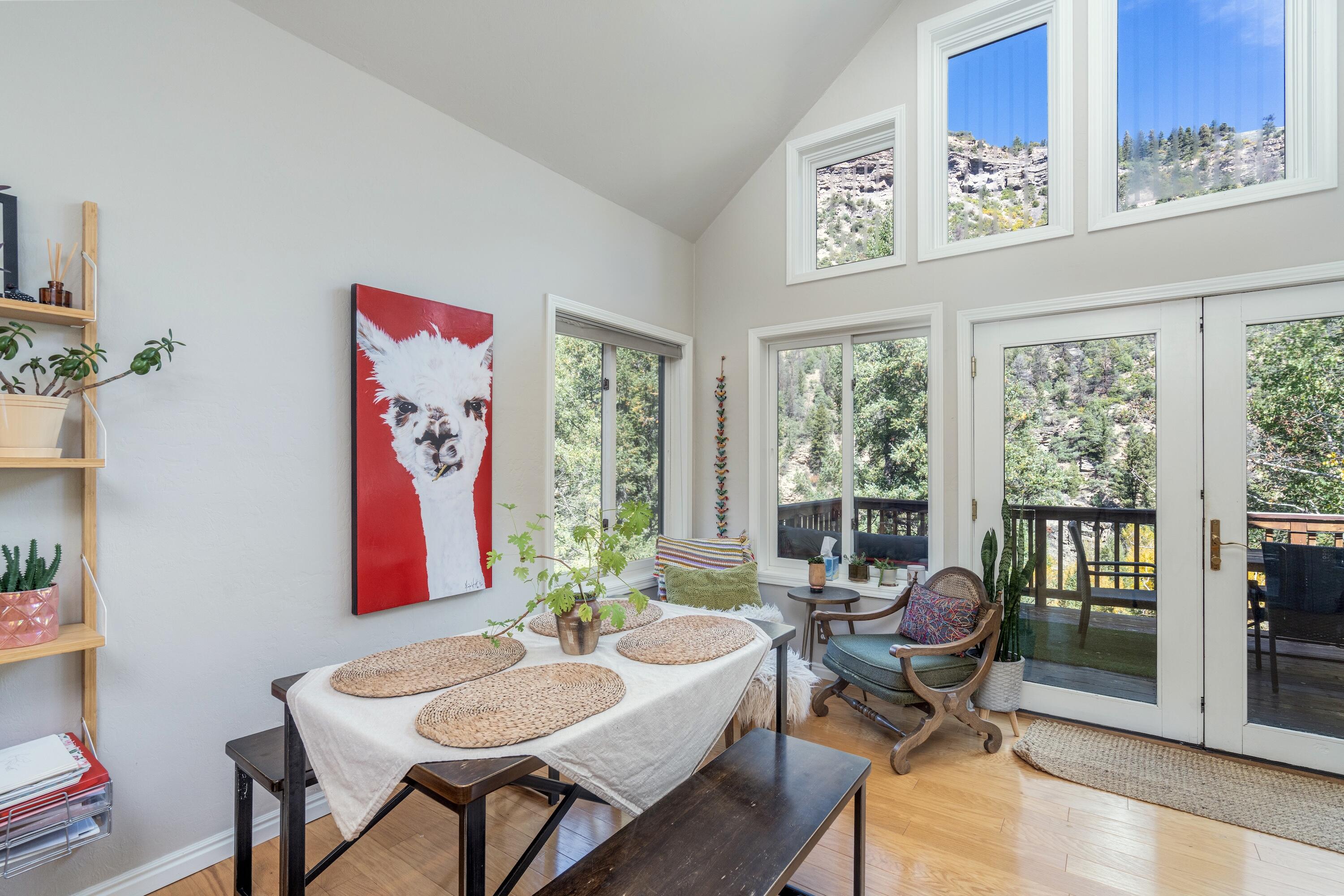 Bright dining nook with a set table, mountain-view windows, and doors opening to a deck.