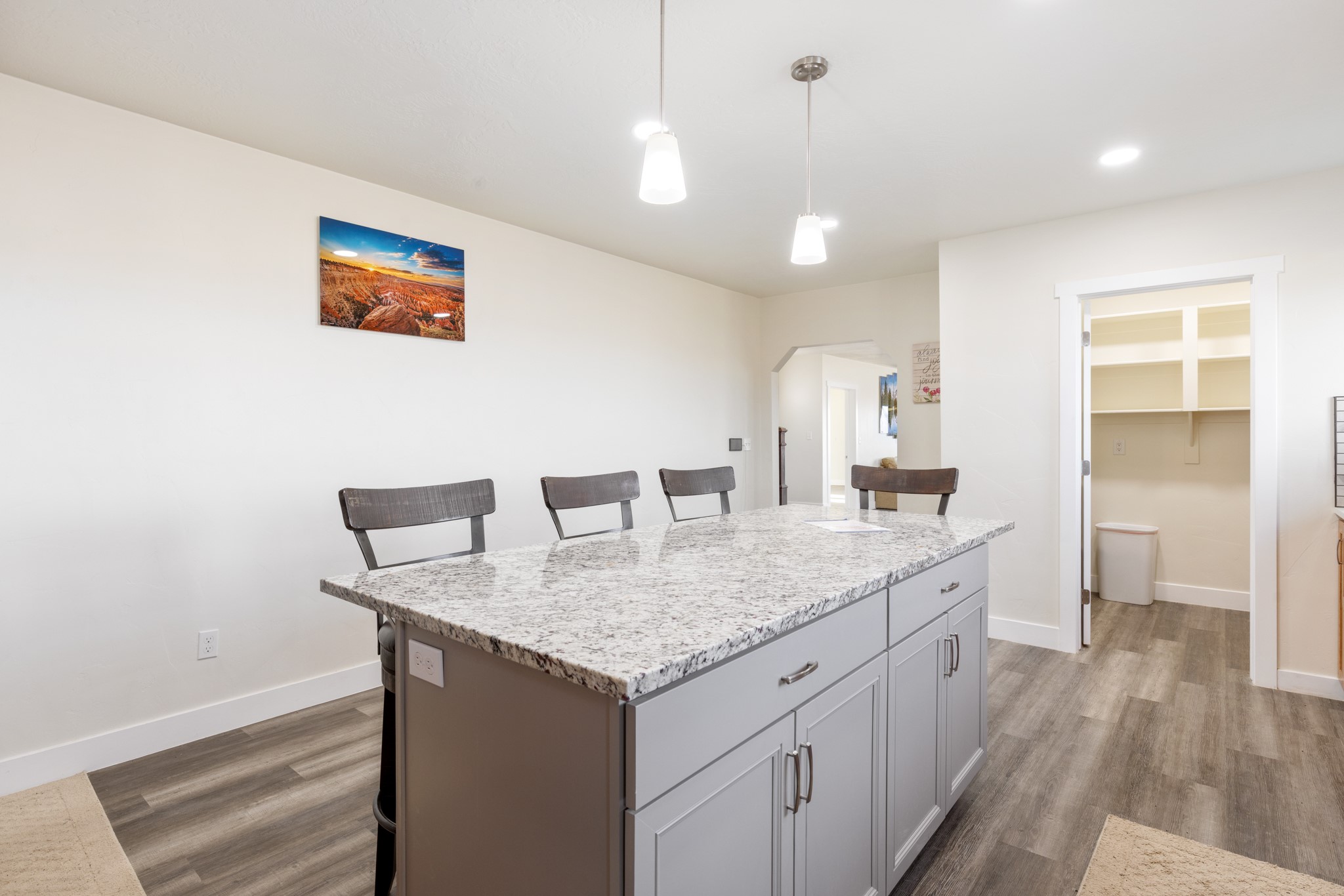 Kitchen with a large granite-topped island, gray cabinets, pendant lights, and an open pantry.