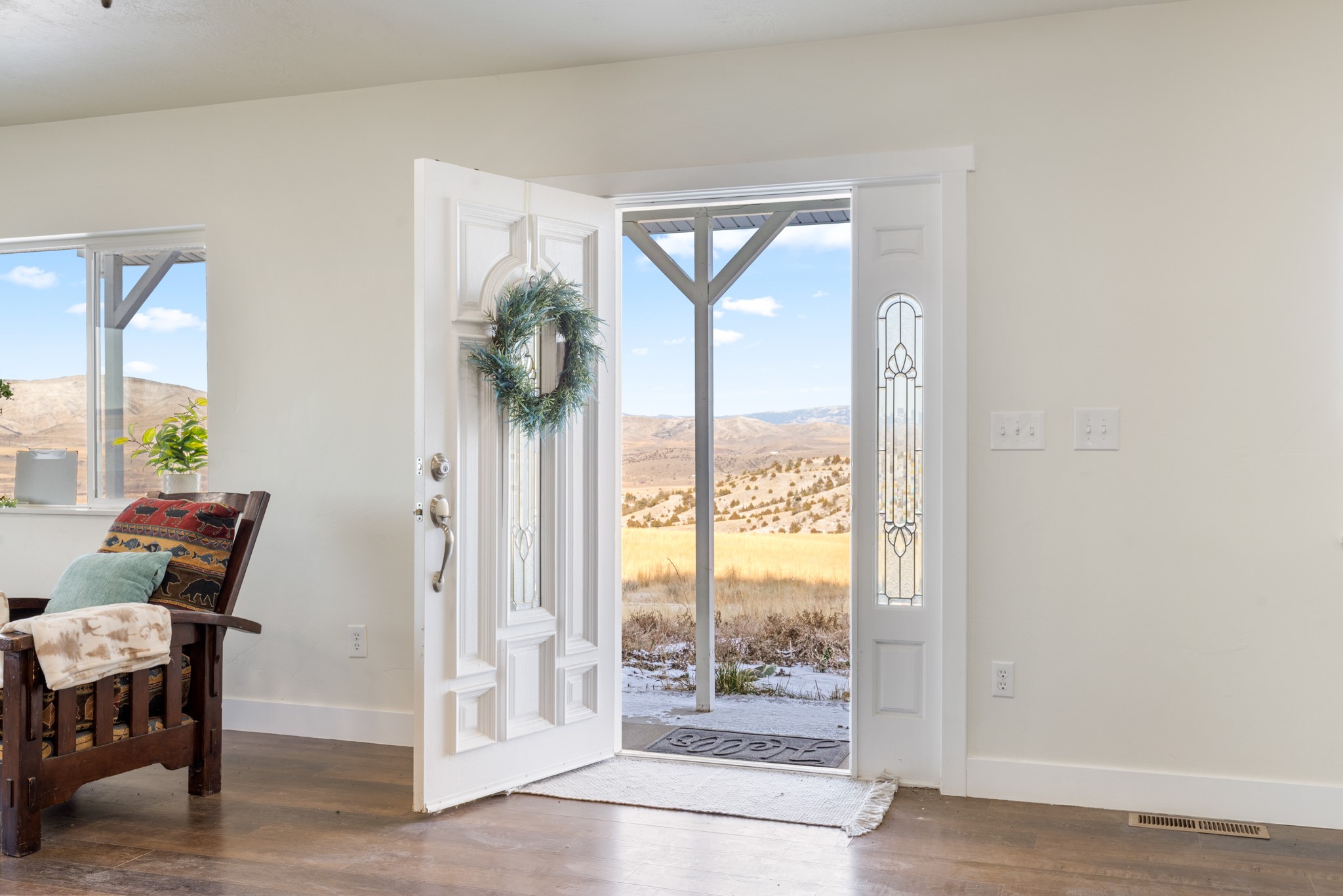 Entryway with an open front door framing a view of snowy ground and rolling hills.