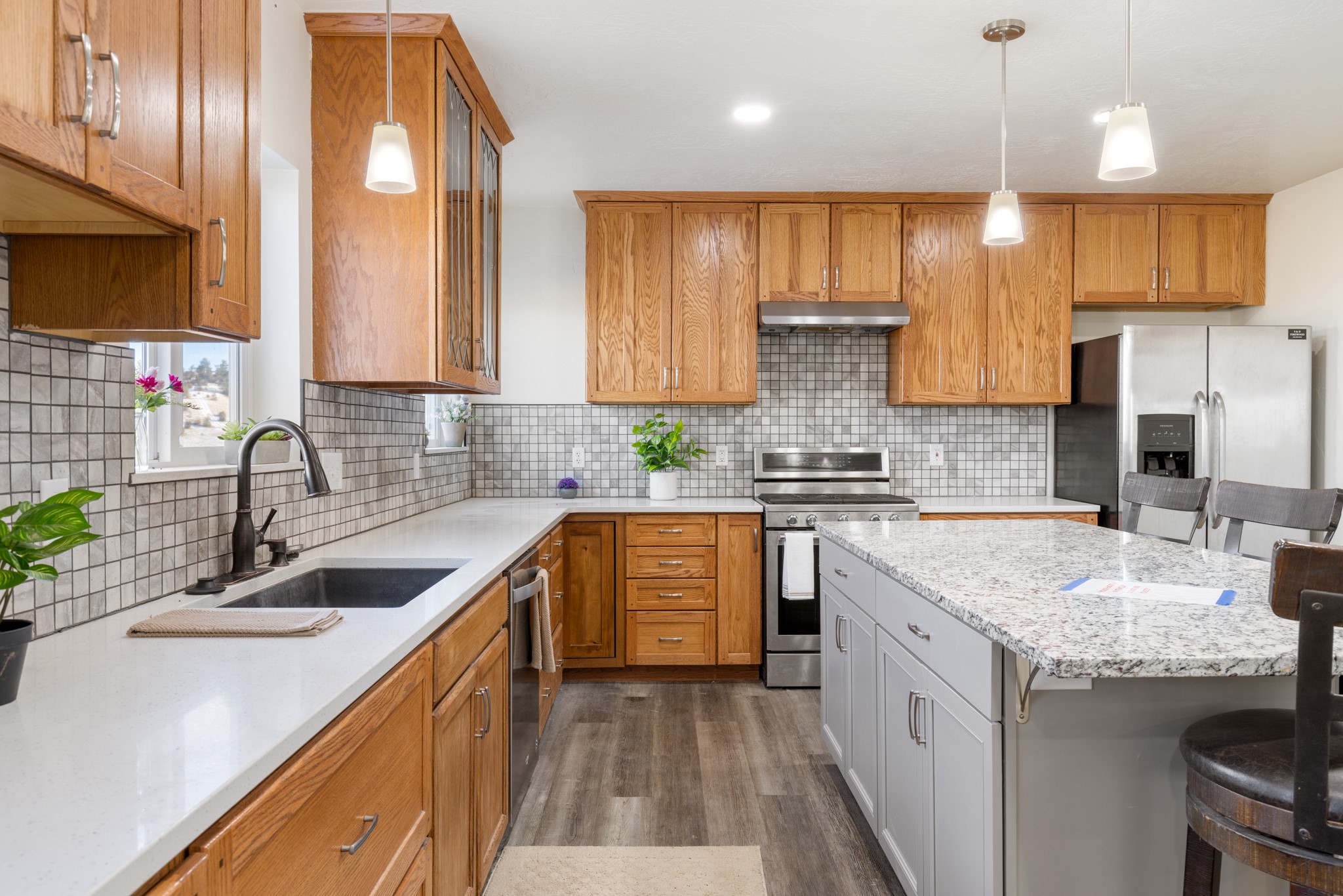 Kitchen with oak cabinets, tiled backsplash, stainless steel appliances, and a large granite-topped island.