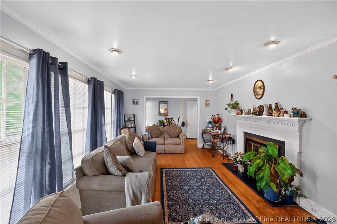 Living room with a white fireplace, hardwood floors, and large windows with blue curtains.
