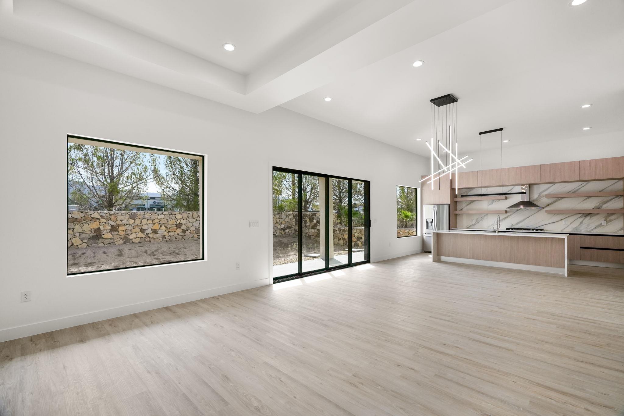 Open-plan kitchen and living area with wood cabinetry, a large island, and black-framed windows.