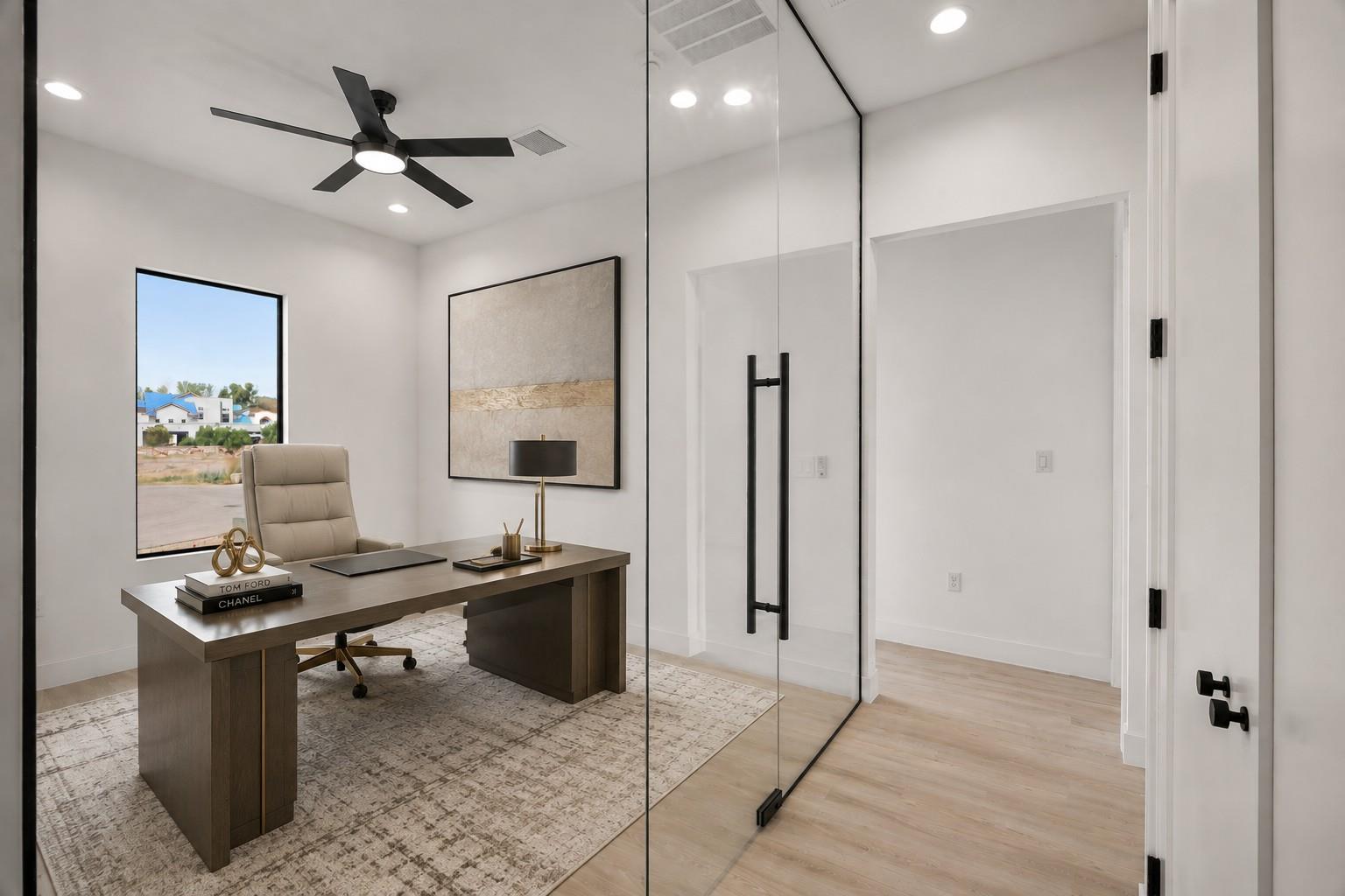 Staged home office with a dark wood desk, patterned rug, and glass partition.